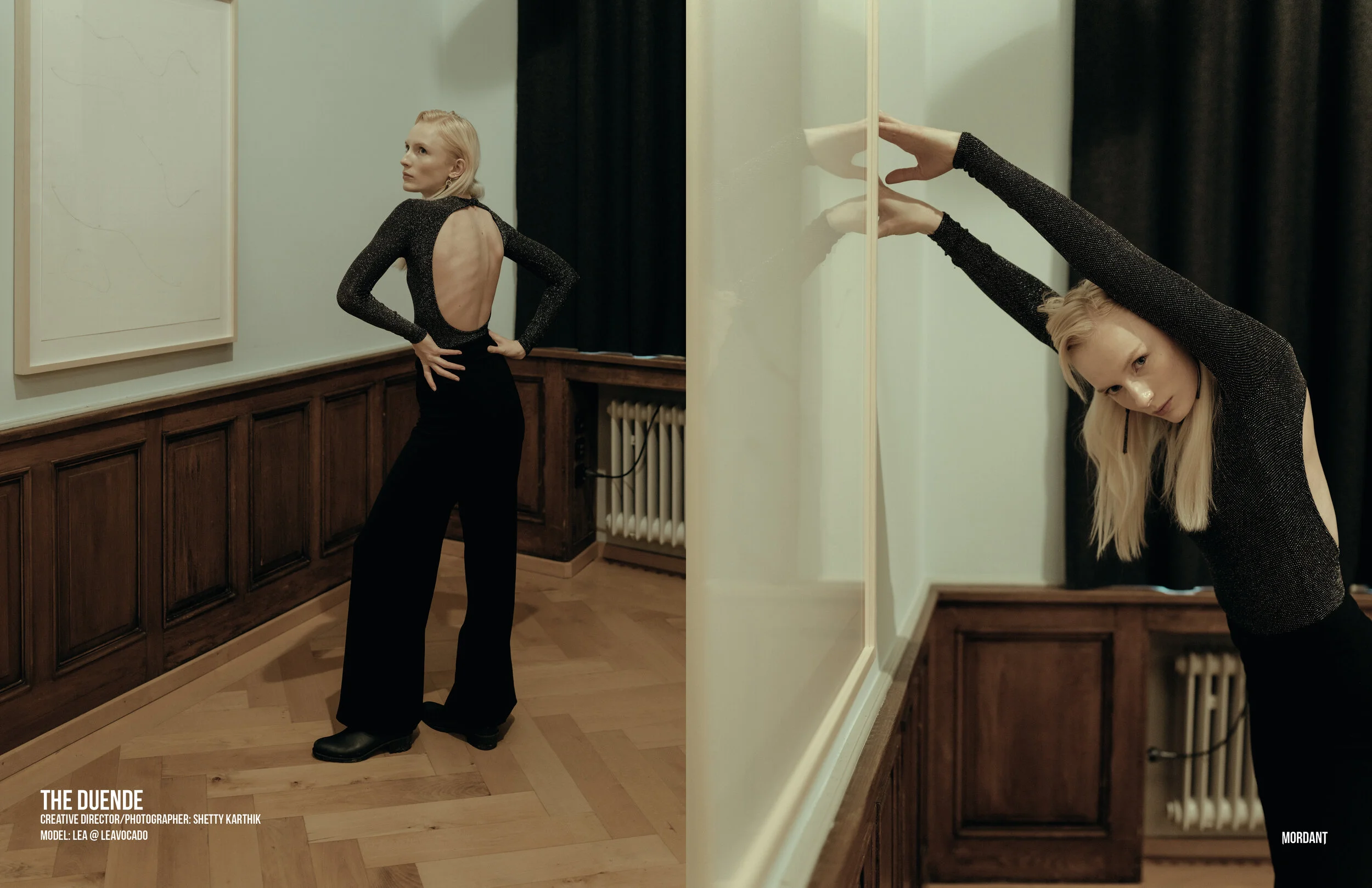 A blonde woman in a black dress with an open back is standing indoors, looking to her left. She has her hands on her hips. The image is split into two parts with her reflection visible in a mirror on the right side, showing her stretching her arms ov