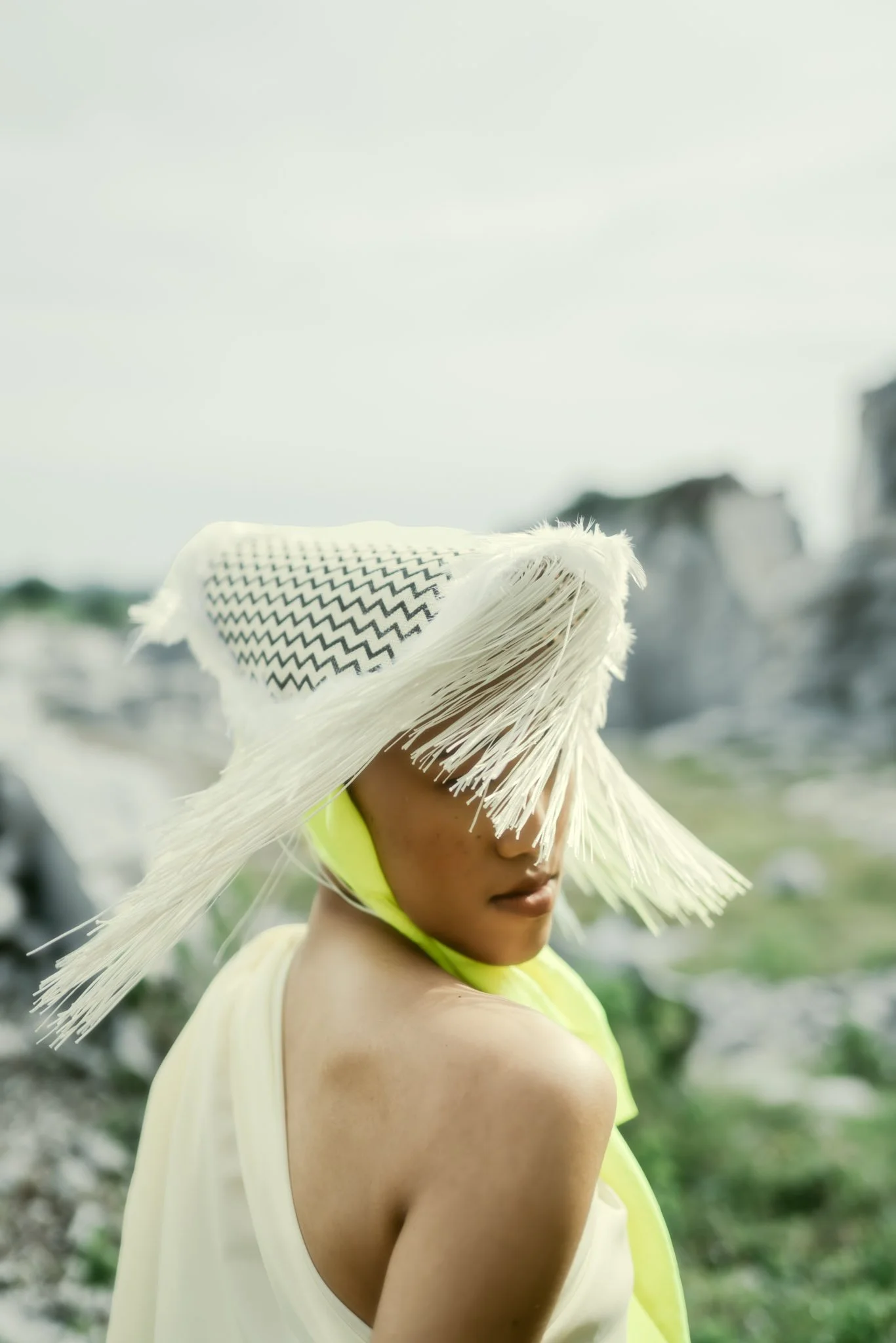 Woman in a large straw hat with a black zigzag pattern, looking over her shoulder outdoors.