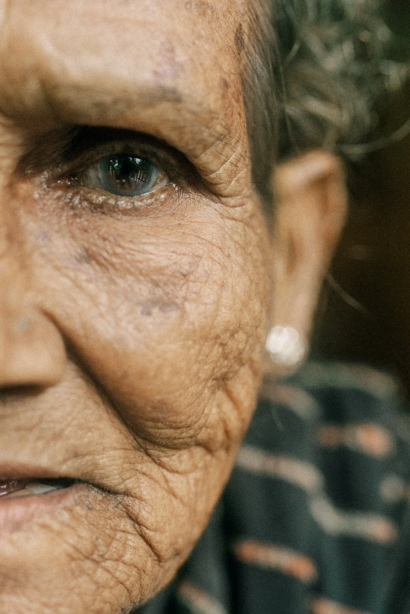 Close-up of a person's face showing their left eye and part of their nose and cheek, with visible skin wrinkles and skin tone.