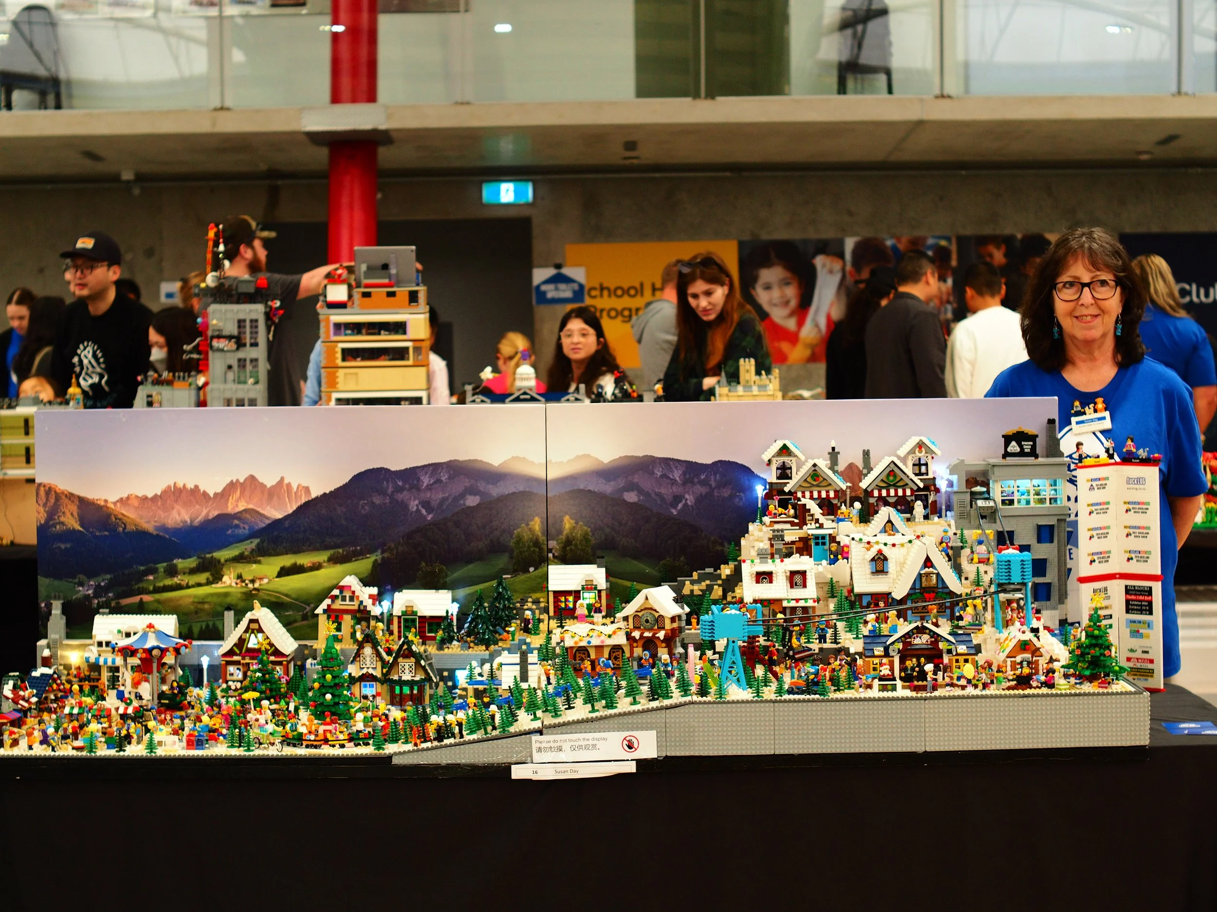 Display of LEGO creations including various buildings, detailed scenes, and a mountain backdrop at a public exhibition.