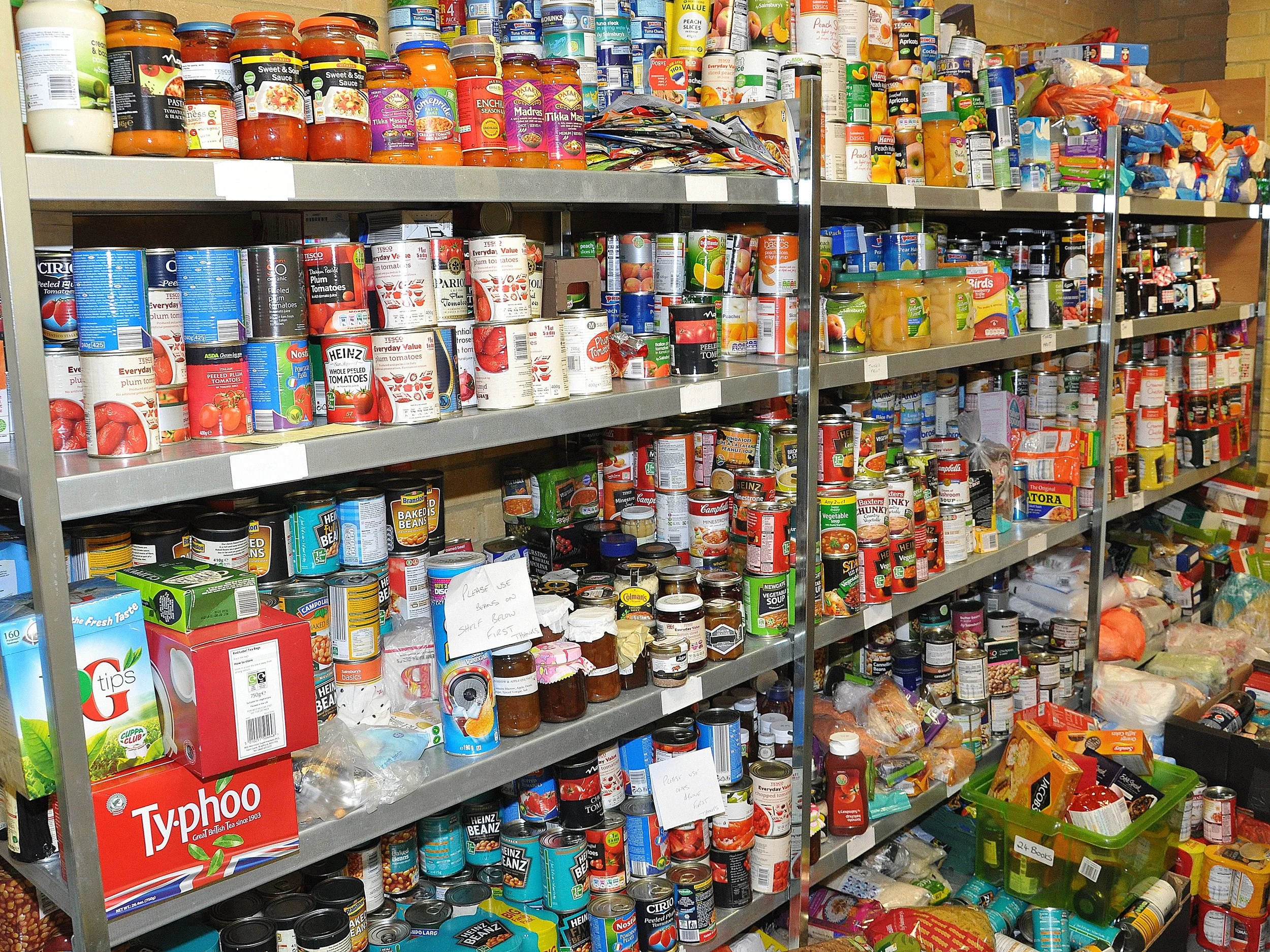 Shelves stocked with various canned goods, jars, and packaged food items in a grocery store.