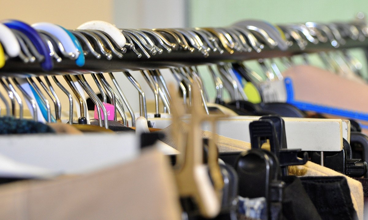A close-up of a clothing rack with various hangers holding different garments.