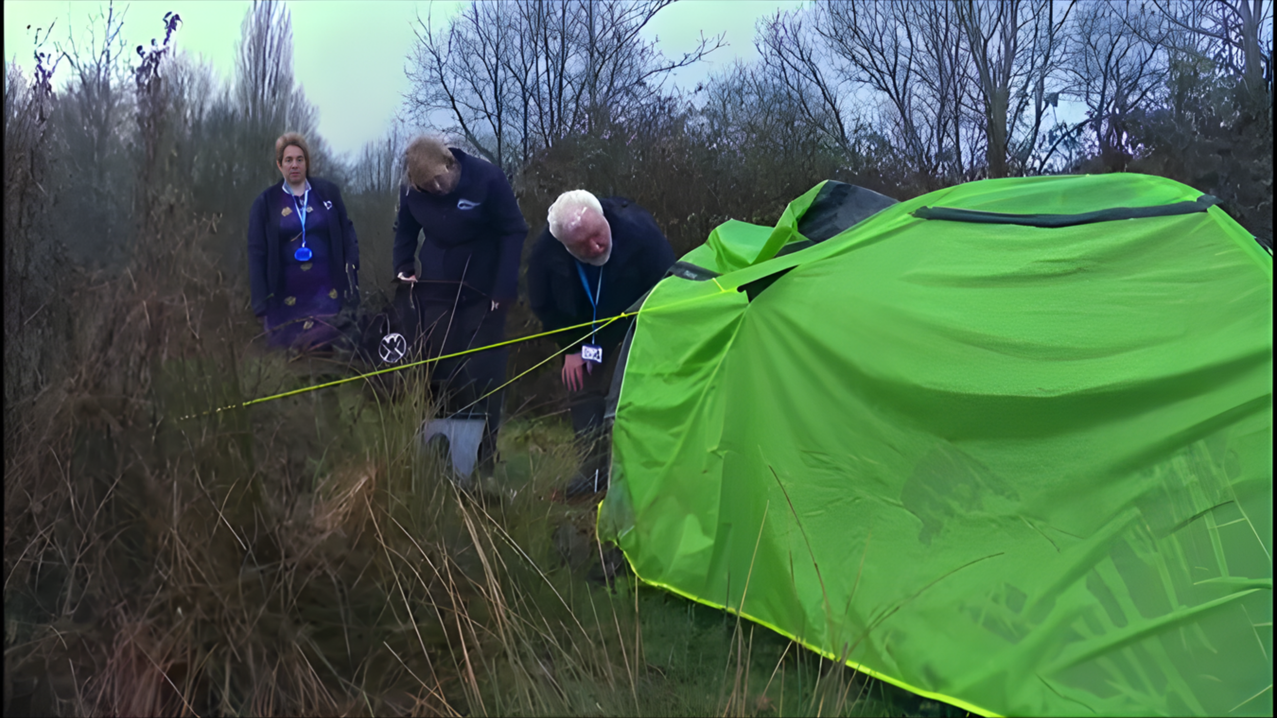 Forensic investigators examining a crime scene in a grassy outdoor area with a bright green tent and yellow police tape.