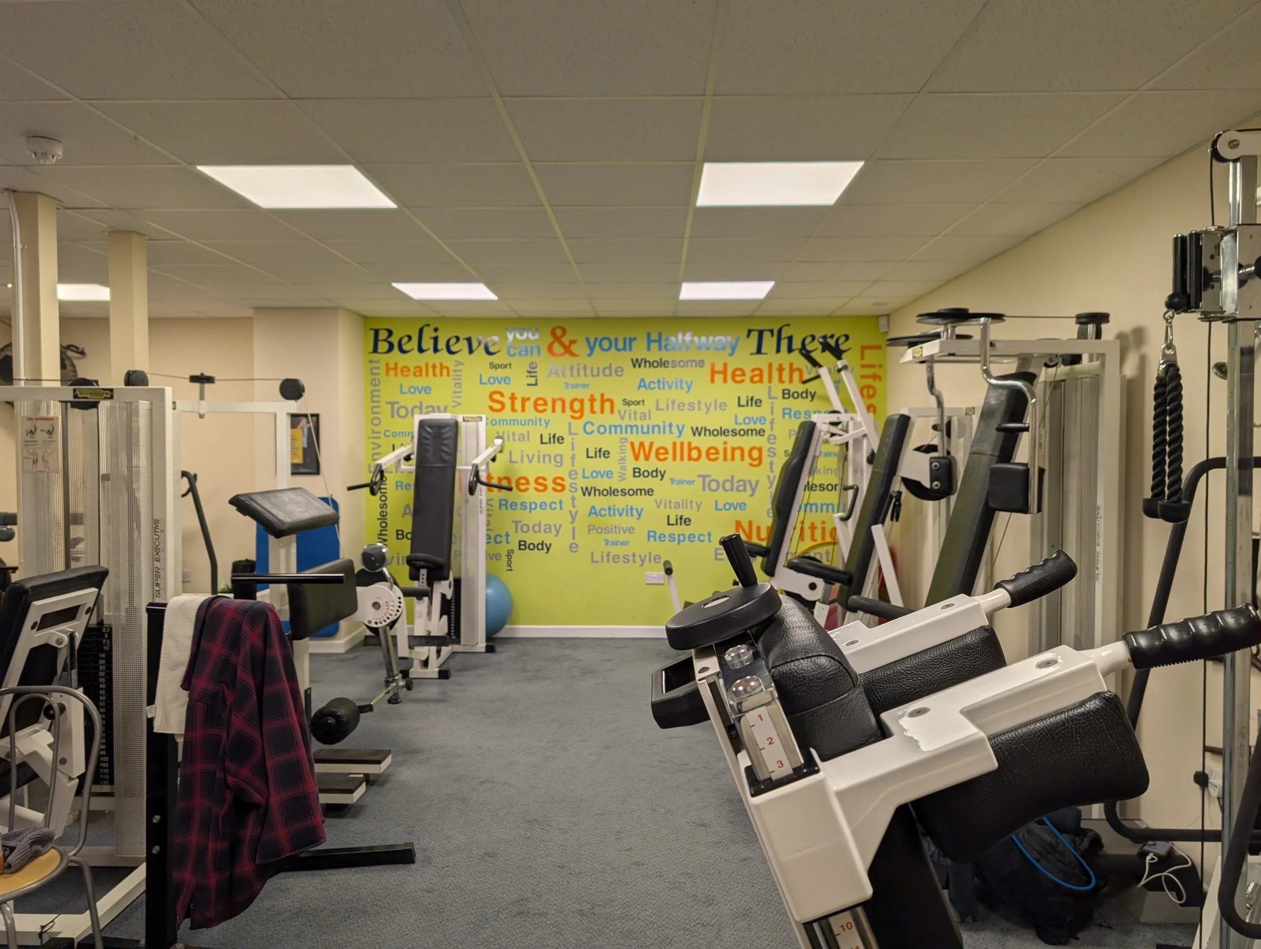 Exercise equipment in a gym with a colorful motivational wall in the background