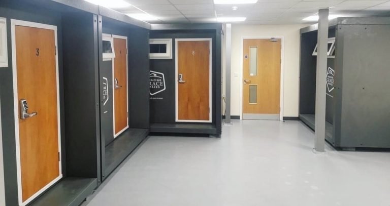 Indoor facility with wooden doors numbered 3 and 5, and a yellow door at the end of the hallway, surrounded by gray walls and lockers.