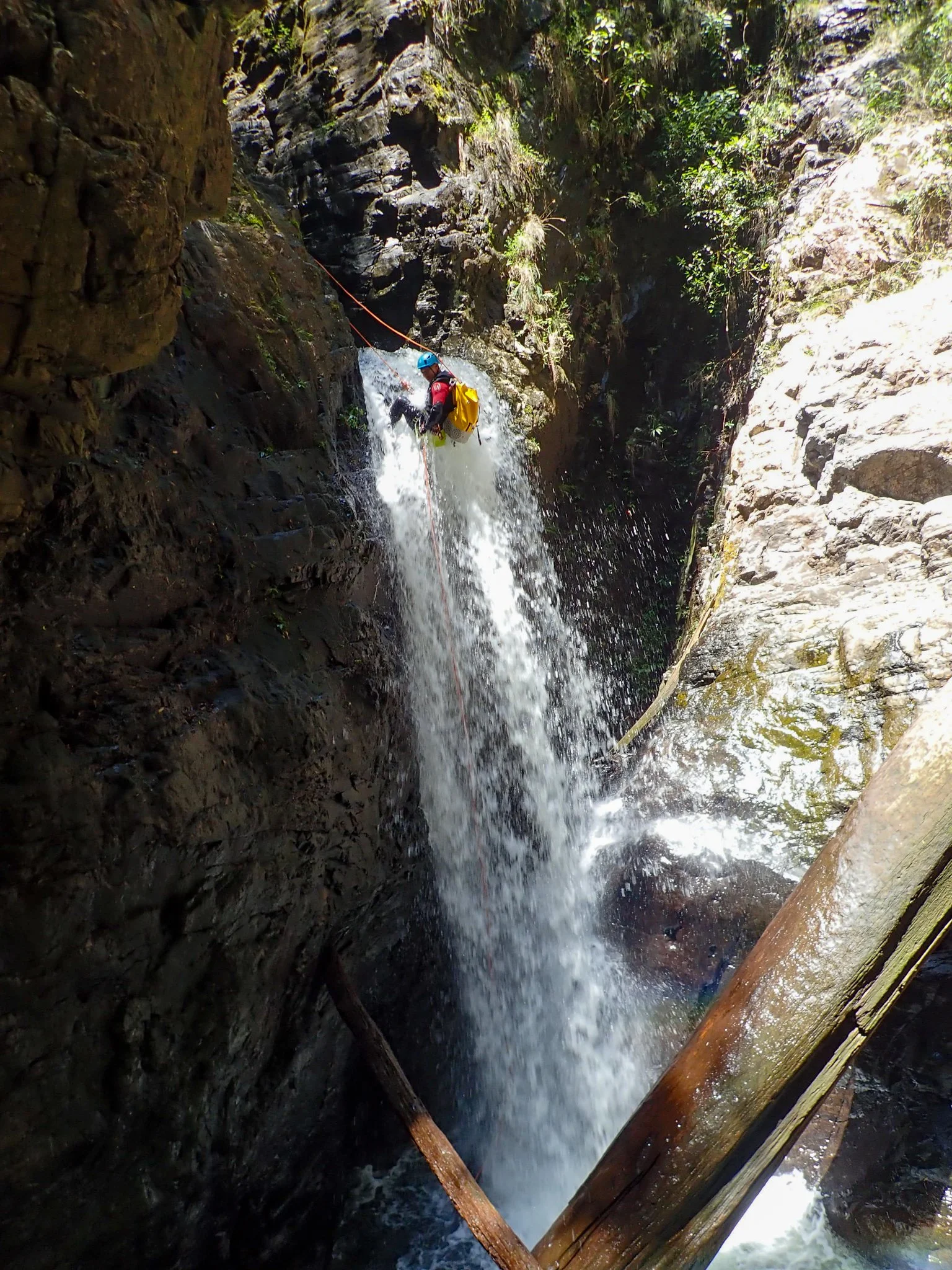 Canyoner abseiling down a waterfall between steep rock walls.