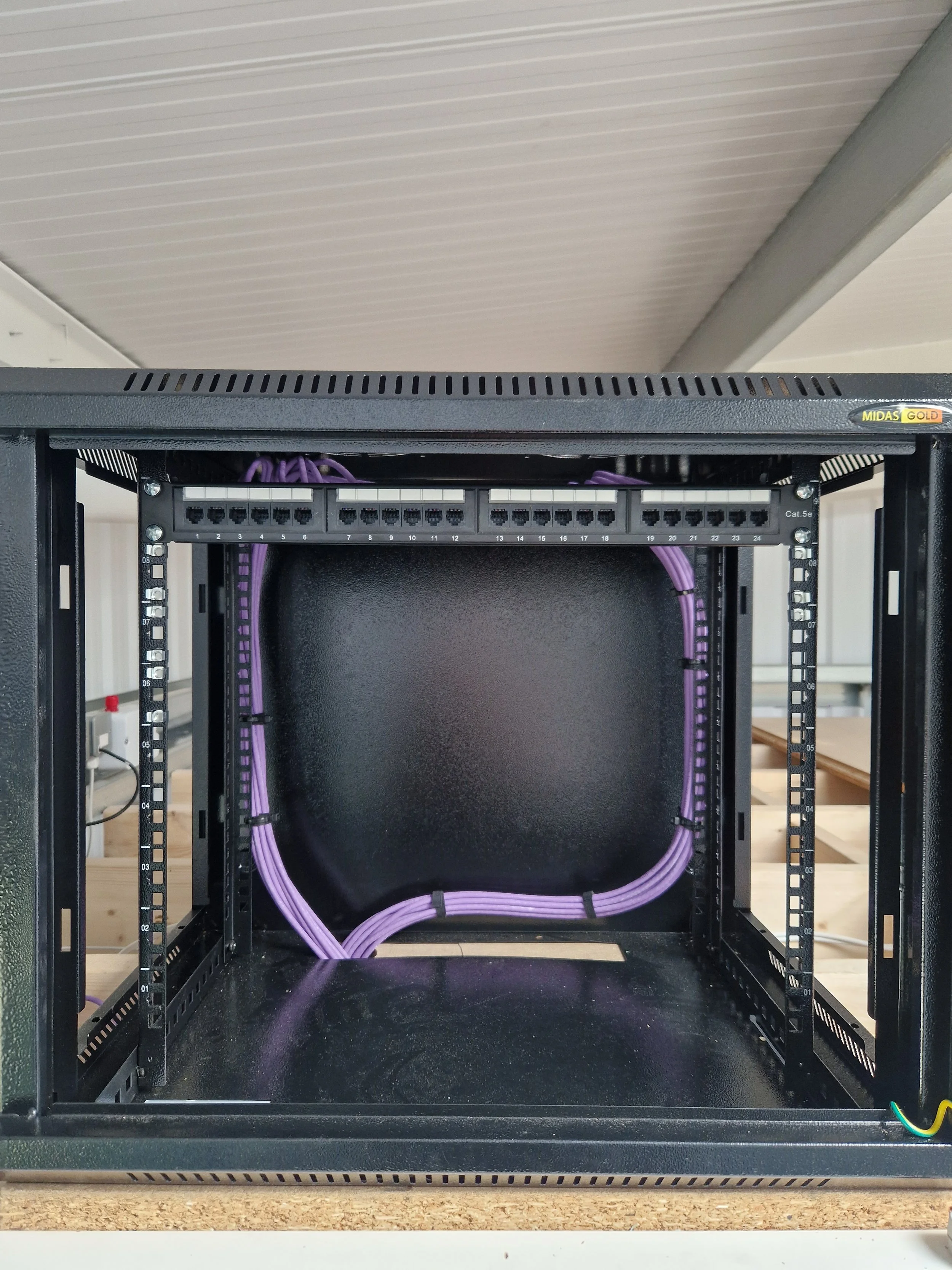 Open server rack with purple Ethernet cables running through it, set on a desk or workbench.