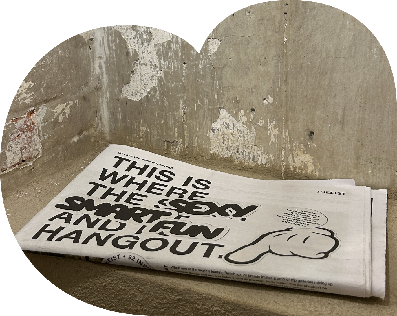 A stack of newspapers on a rough concrete surface with a brick wall in the background. The front page headline reads, 'This is where the sport is, and I hang out,' with a quote from THE LIST and a graphic of a hand pointing downward.