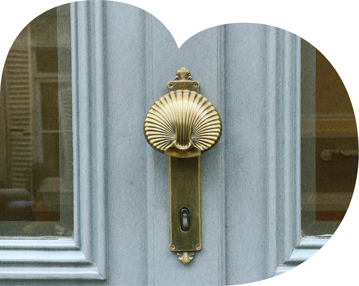 Close-up of a brass door knocker shaped like a shell on a blue door.