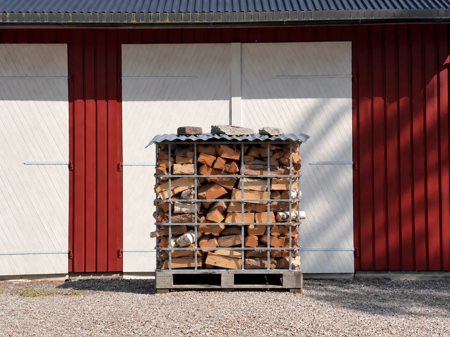 Vedstabler utenfor en bygning med rød og hvit utvendig vegg.