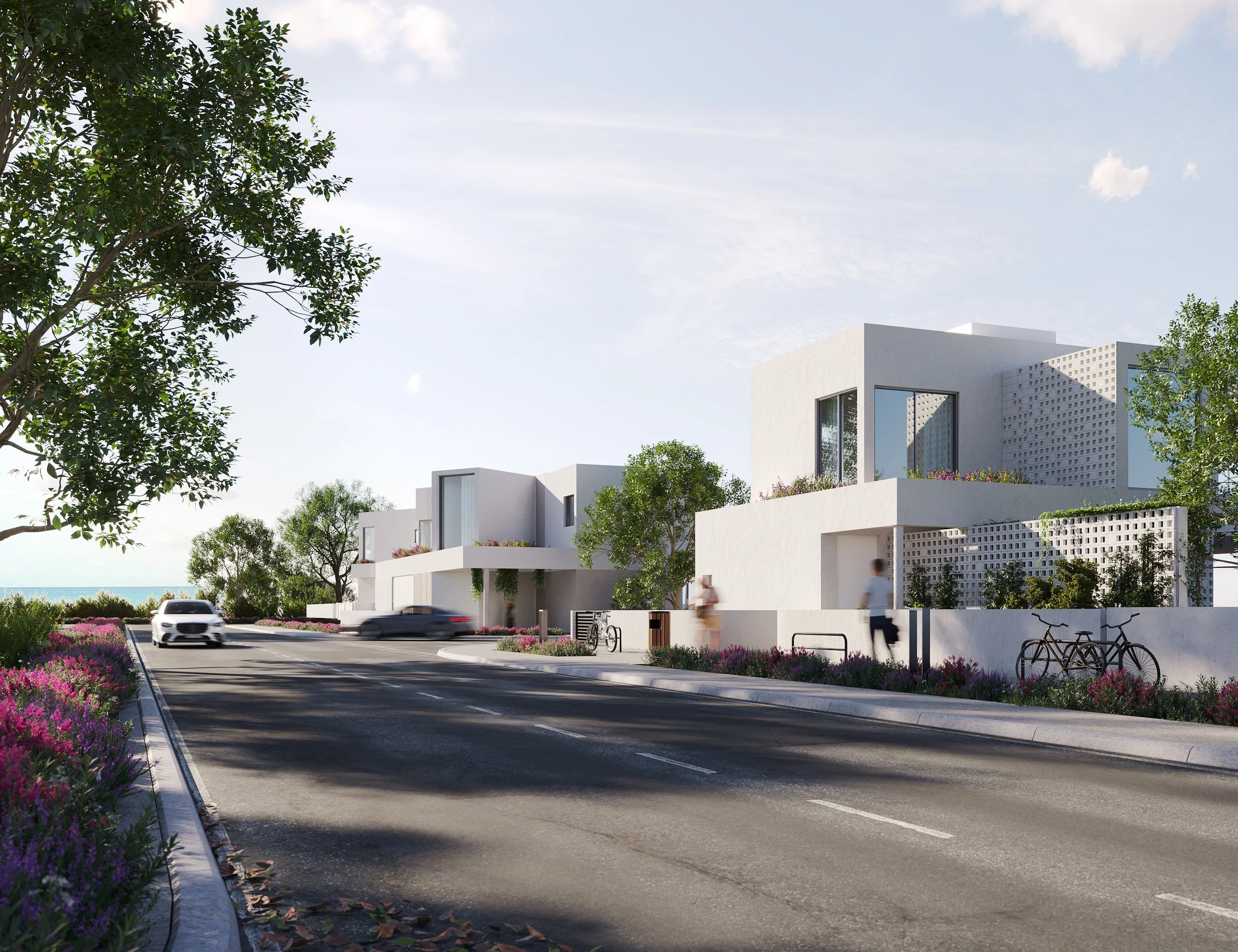 Modern white mediterranean homes residential with large windows and decorative, surrounded by trees and pink flowering bushes, along a paved street with cars and bicycles, under a clear sky with light clouds. Beachside luxury villa getaway in Cyprus.