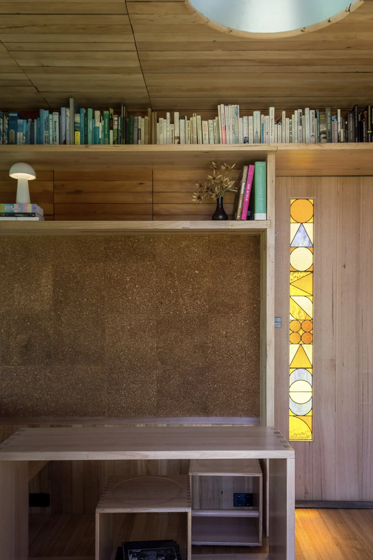 Wooden interior with a stained glass window featuring geometric shapes and vibrant colors, located on a wooden wall.