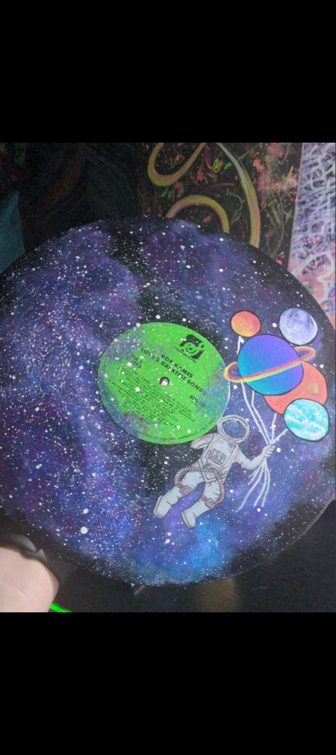 A vinyl record with a colorful outer space design featuring planets and an astronaut holding balloons.