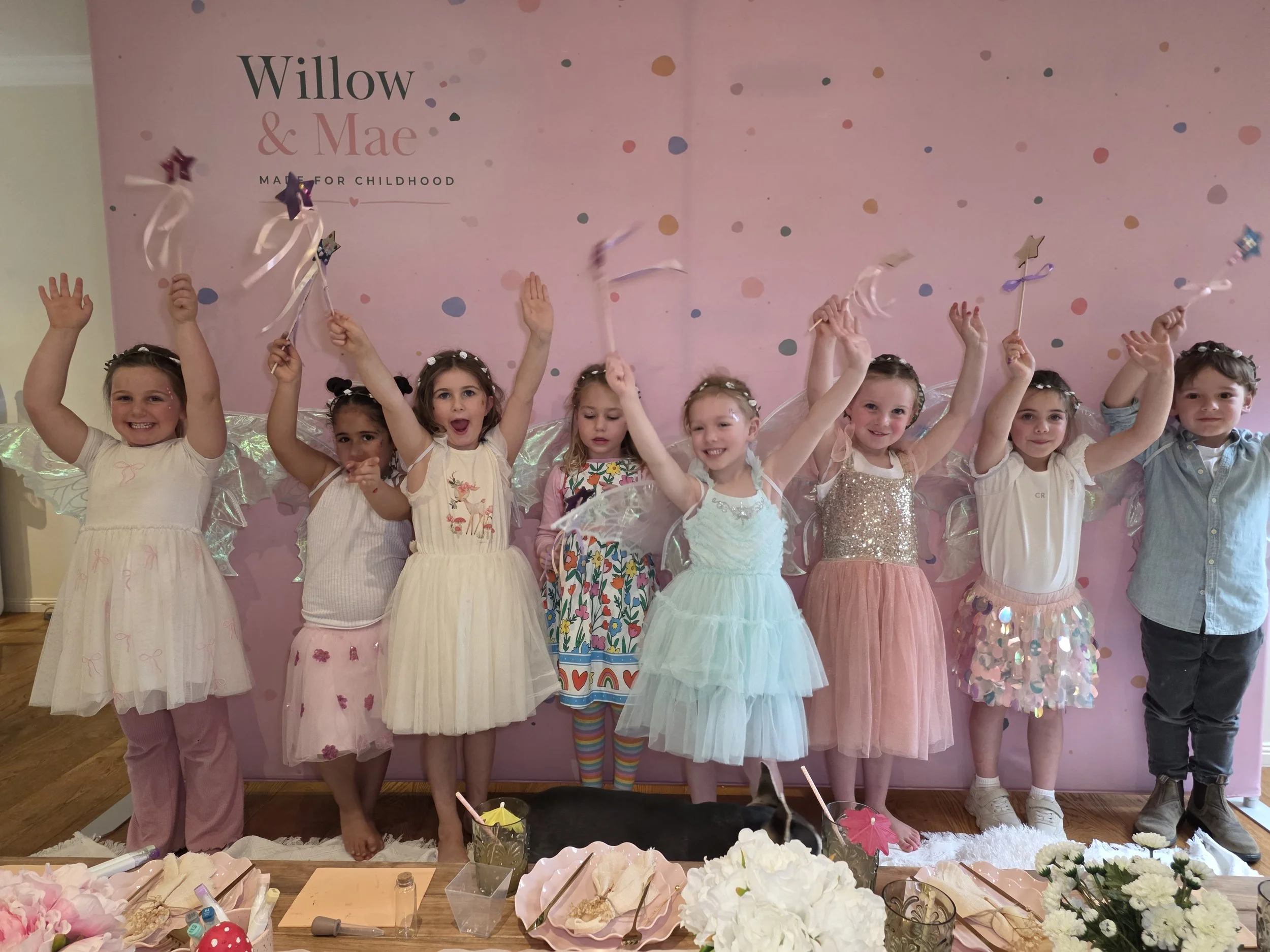 Fairy party guests cheering with their wands at the Willow & Mae photo wall