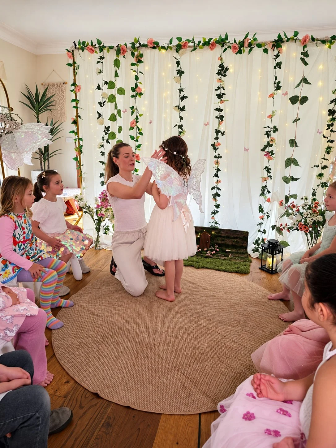Party host fitting fairy wings on a girl in the fairy circle