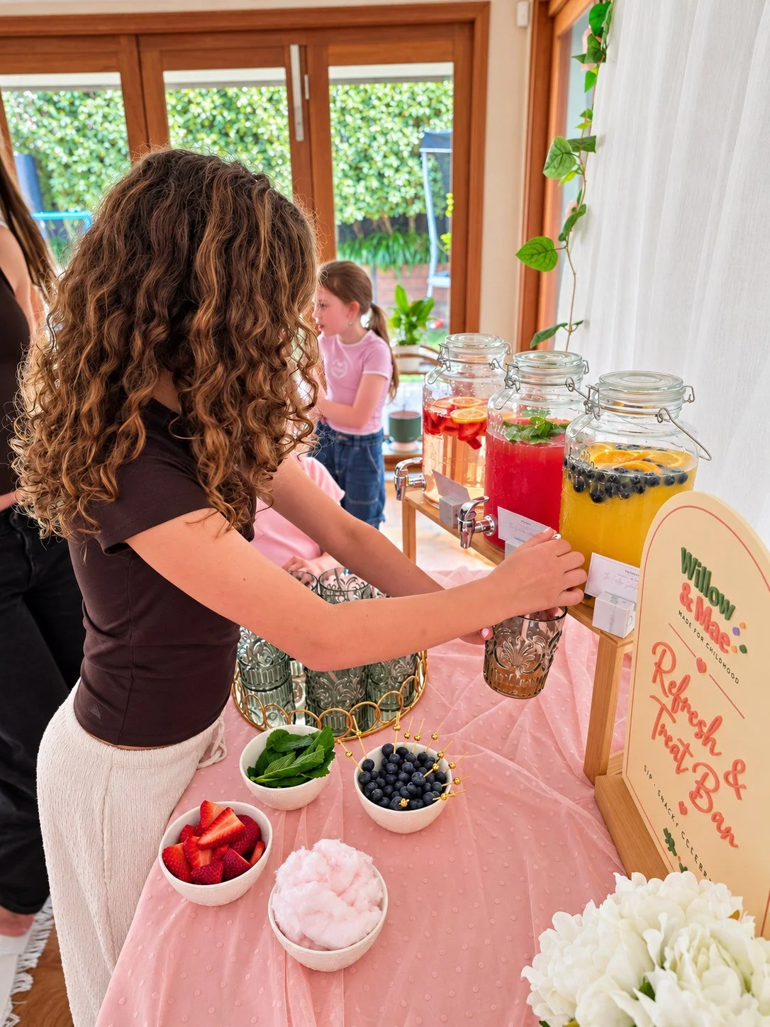 Girl filling her glass at the Refresh & Treat Bar with fresh berries and fruit garnishes