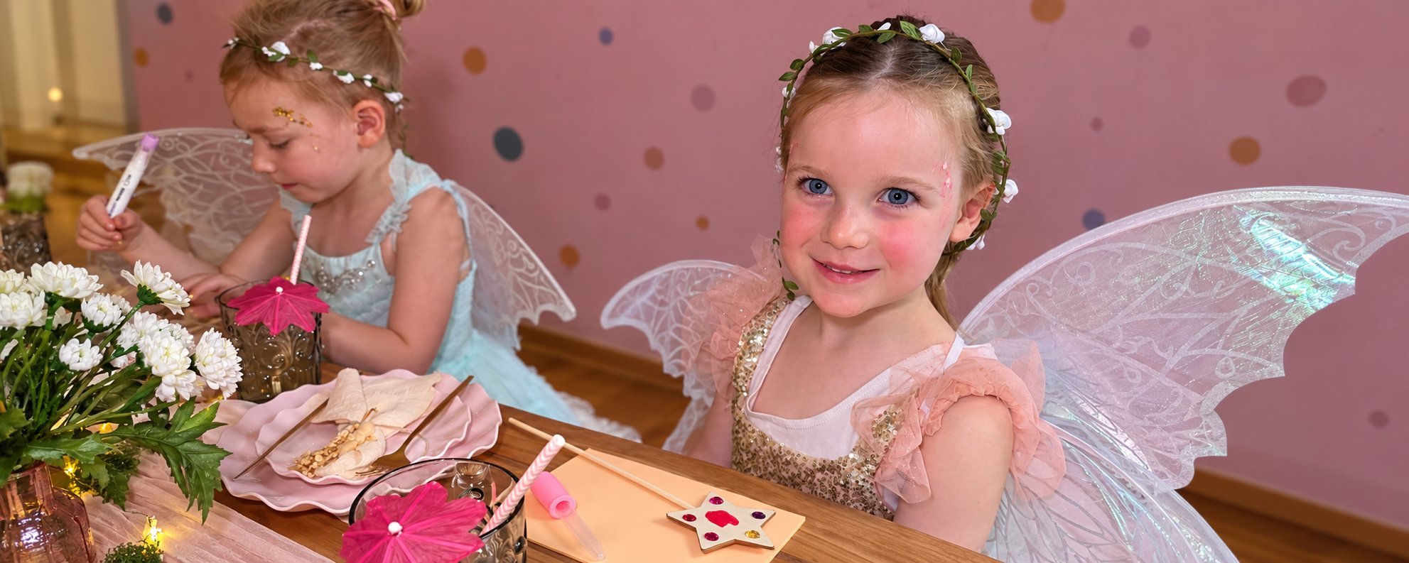 Two little fairies in wings and flower crowns at an Enchanted Garden party table