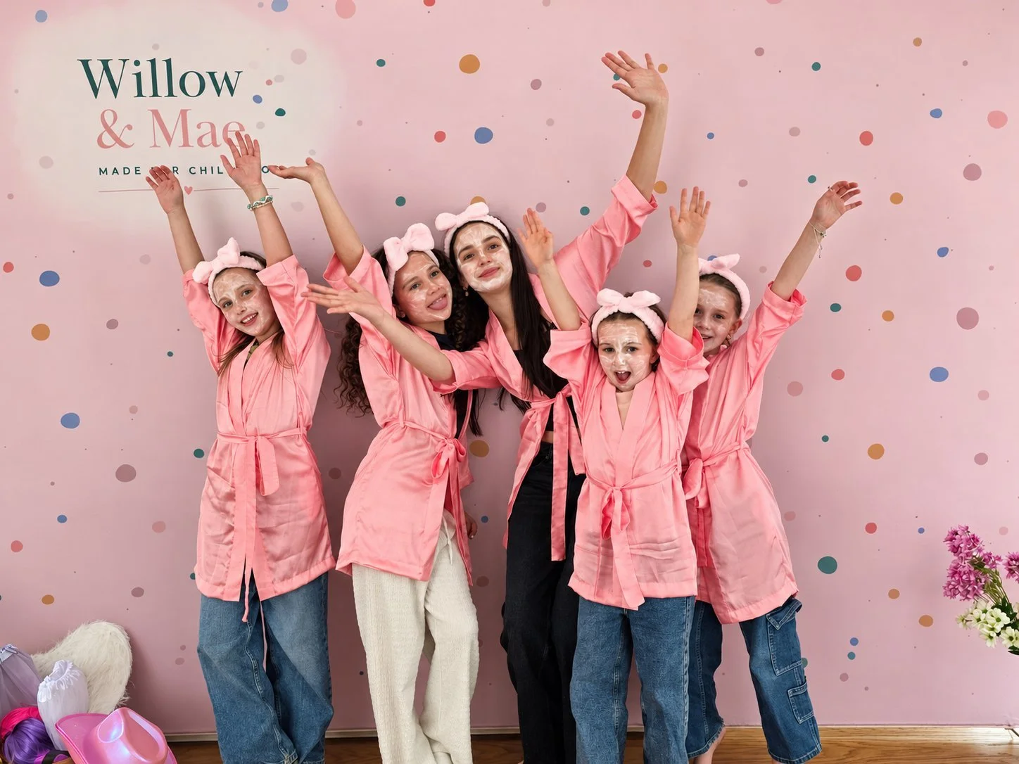 Spa party guests cheering in matching pink robes and face masks