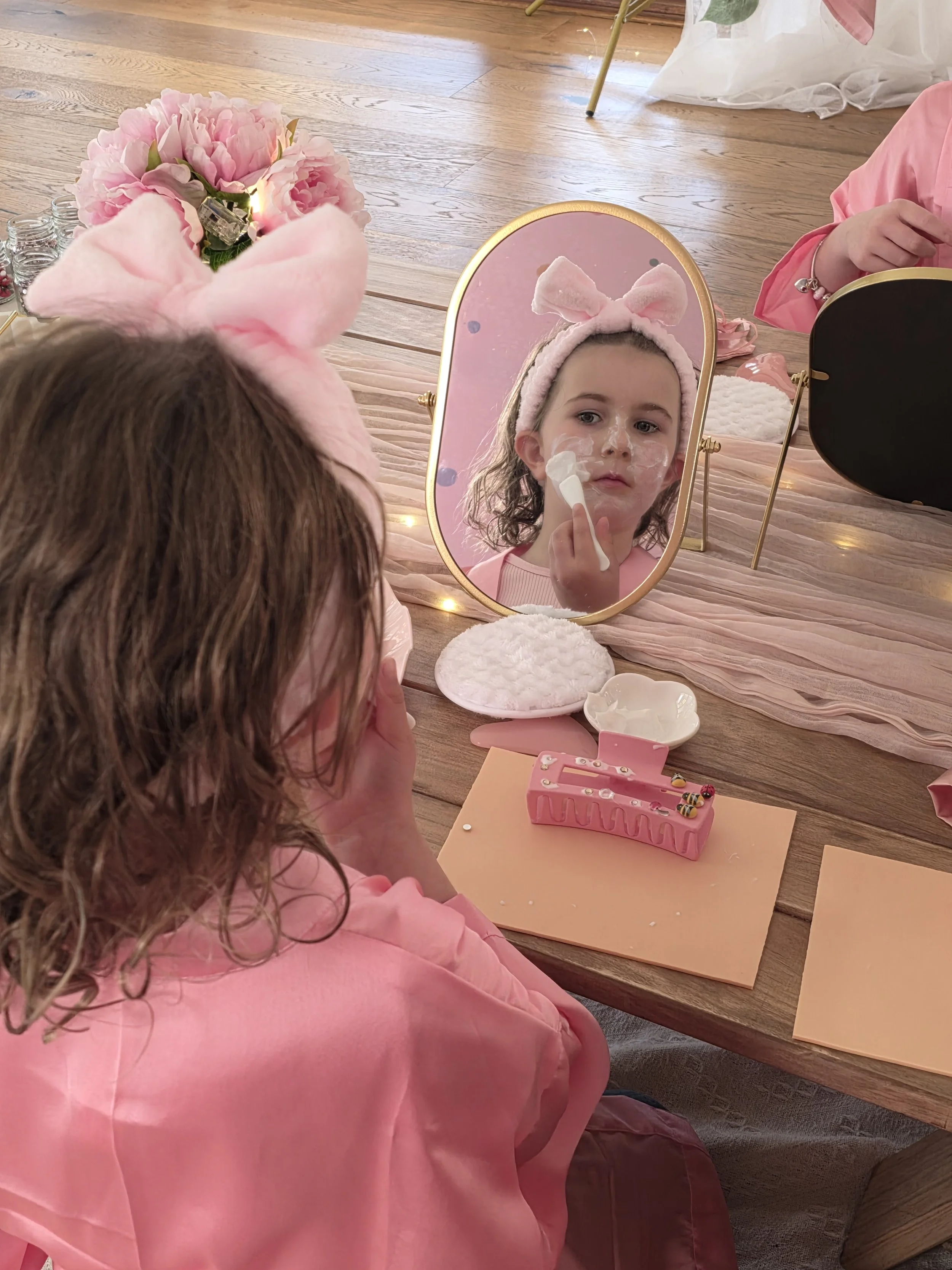 Spa party guest applying a face mask in a gold mirror