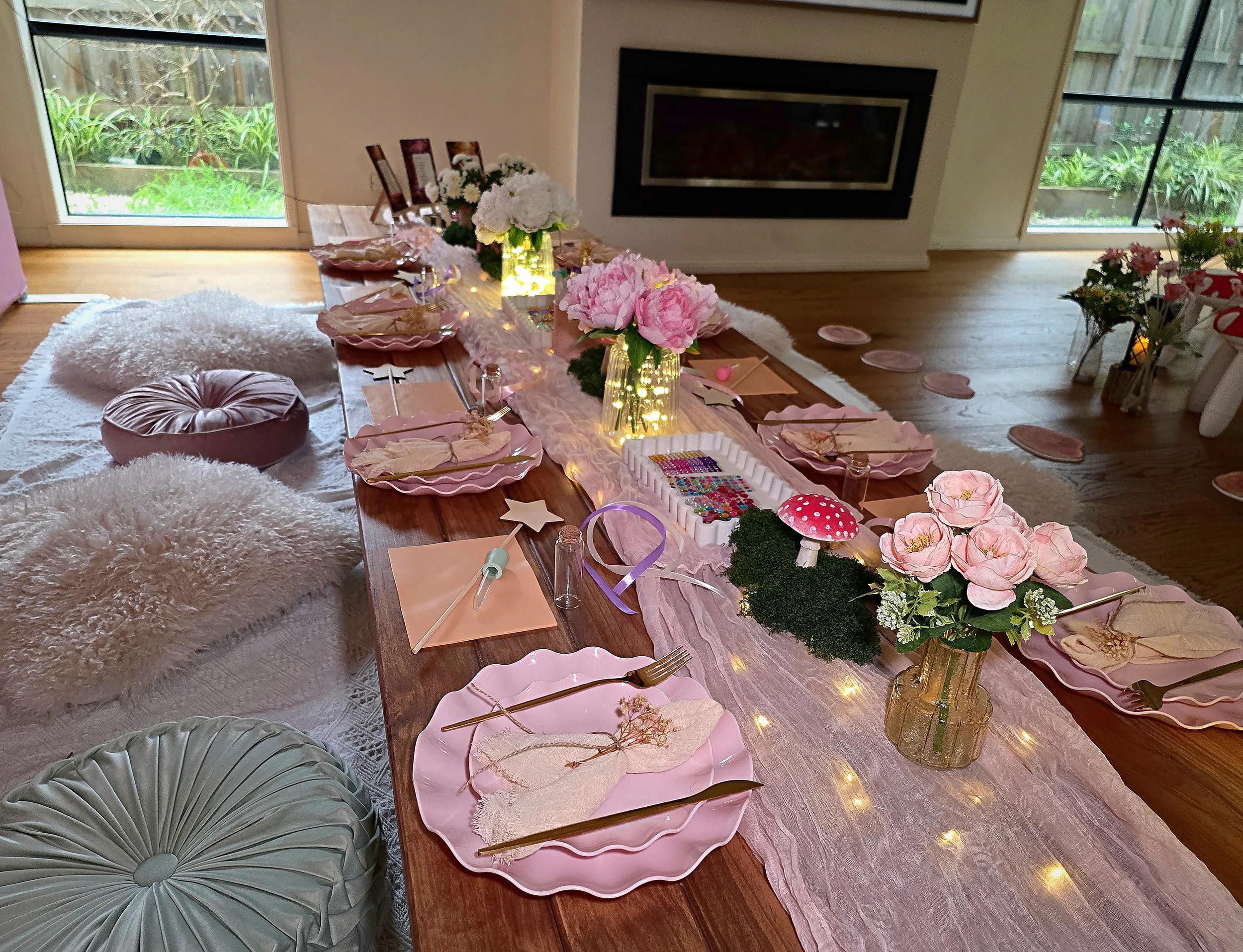 Enchanted Garden table setting with pink scalloped plates, roses, toadstools and fairy lights