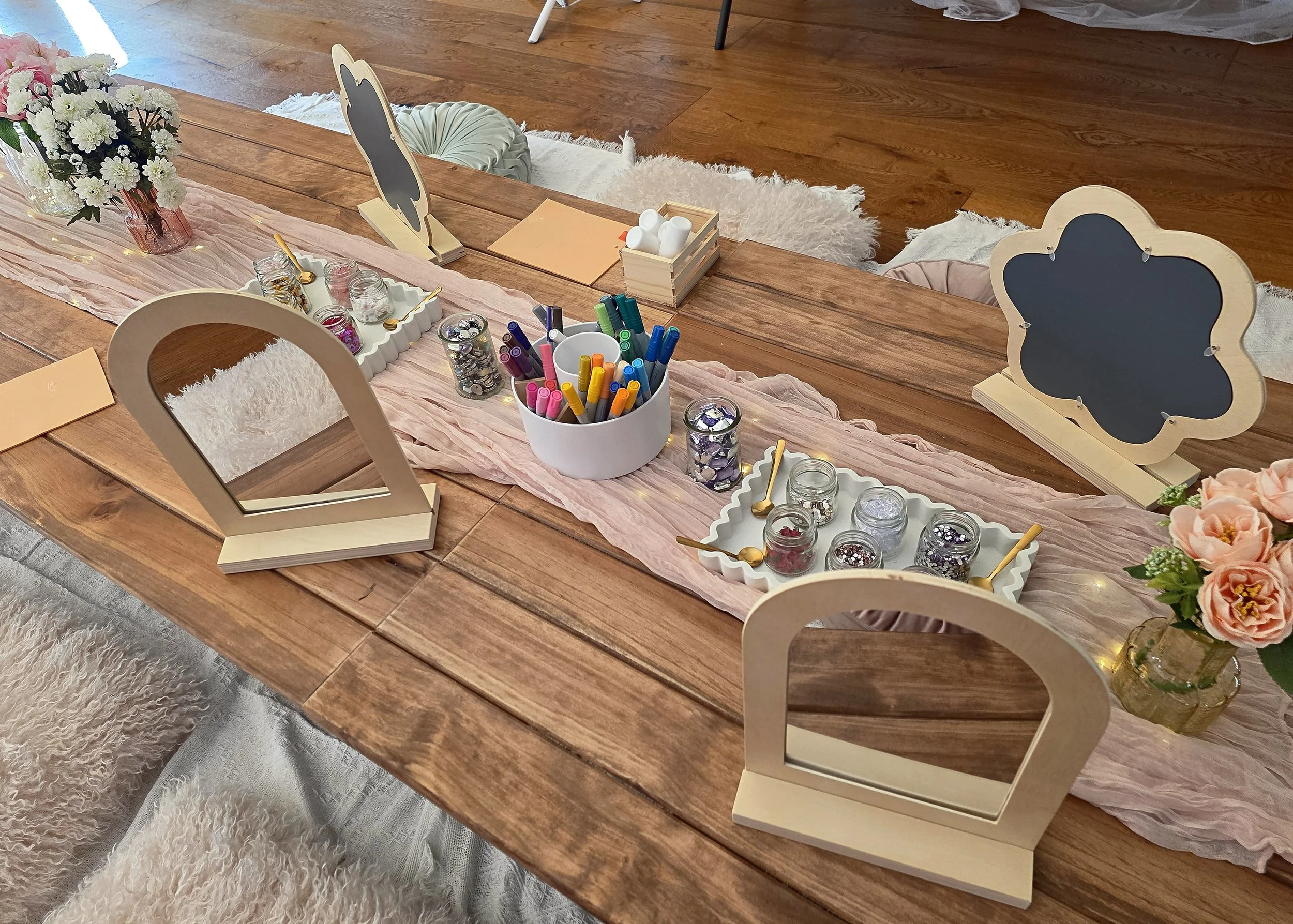 Craft party place settings with blank wooden mirrors, paint pens and gem trays