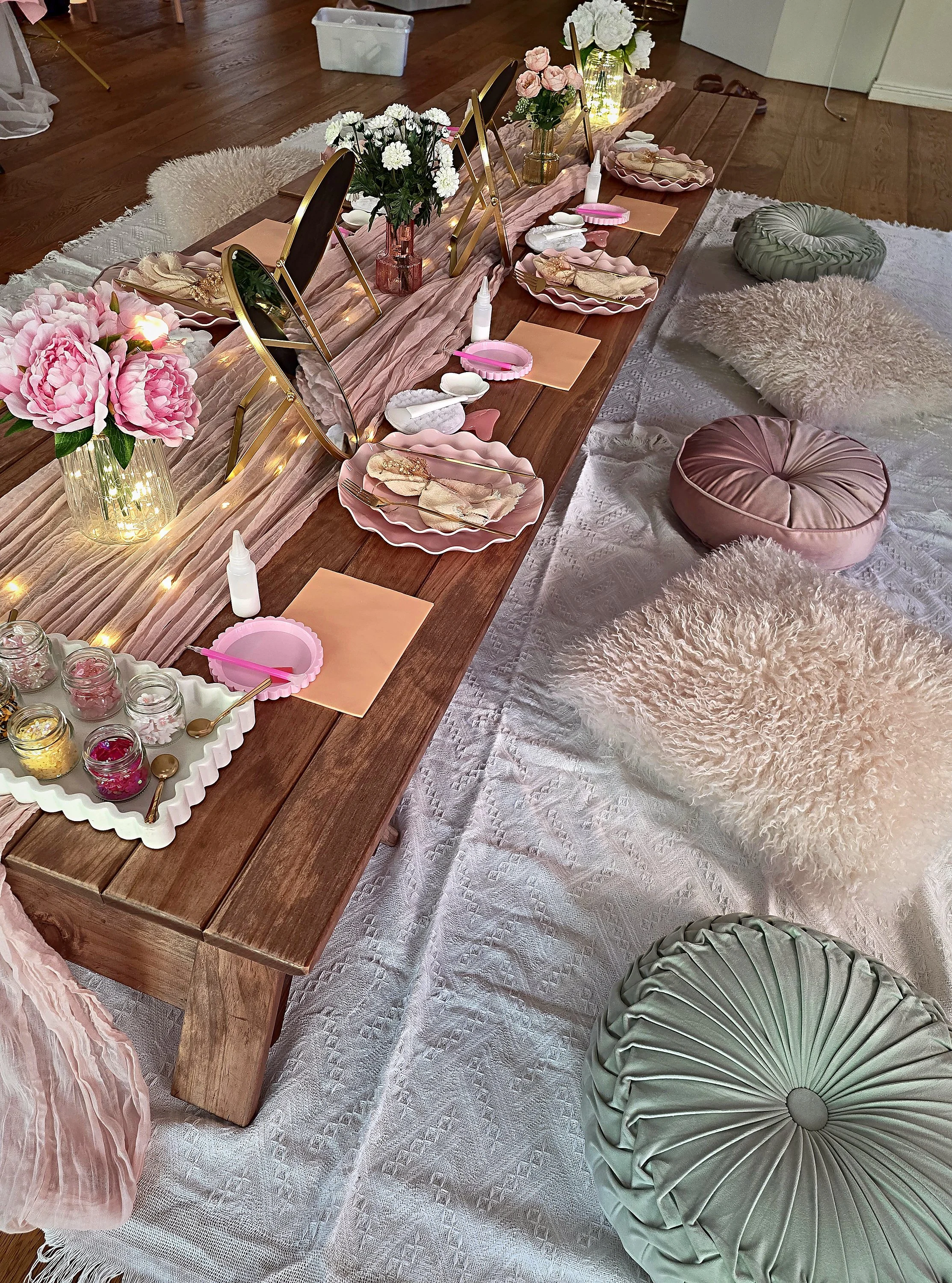 Long low spa party table with pink plates, mirrors, roses, velvet and faux fur cushions with boho rugs