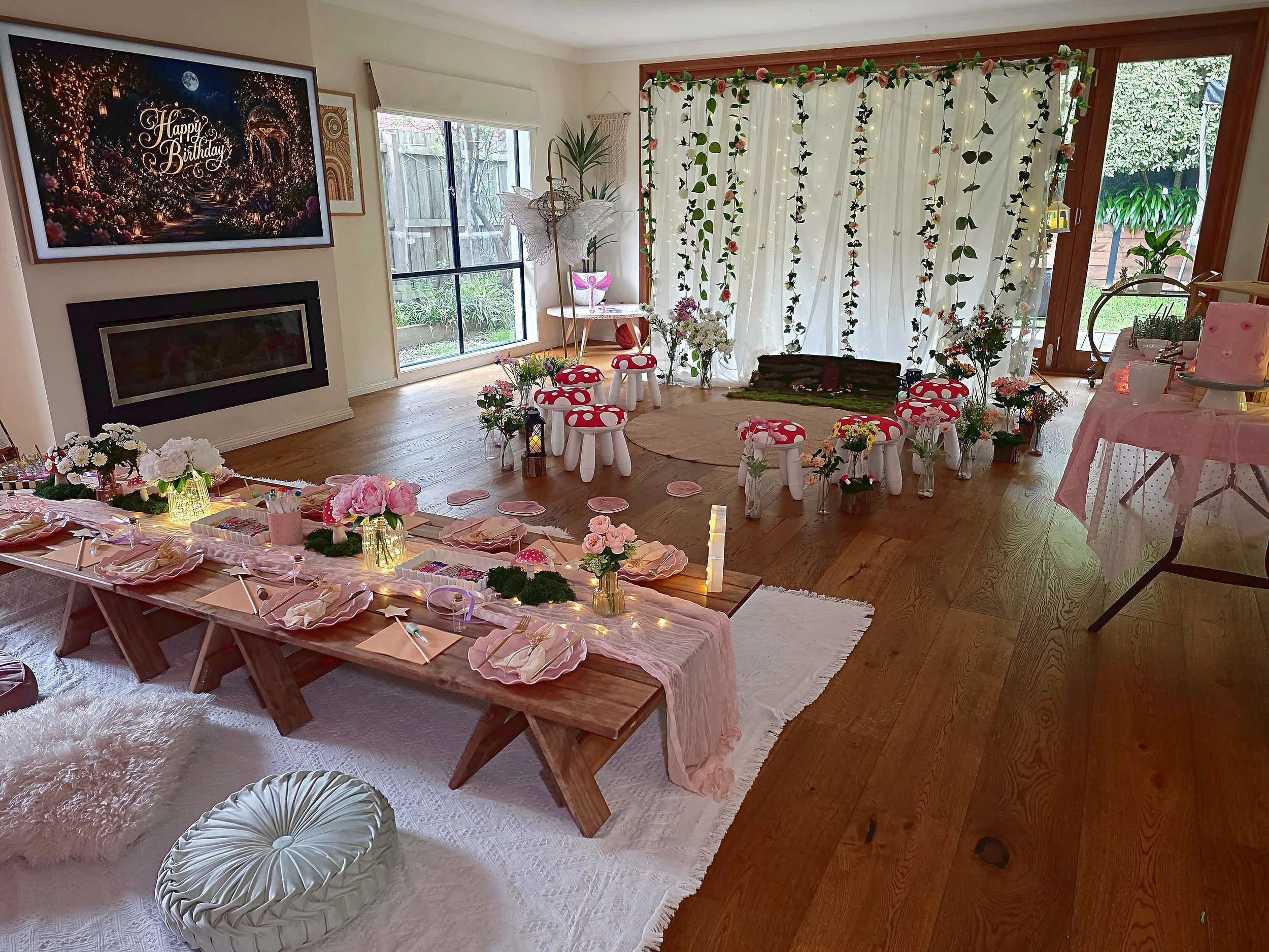 Enchanted Garden fairy party room with a low banquet table, toadstool stools and a curtain of hanging vines