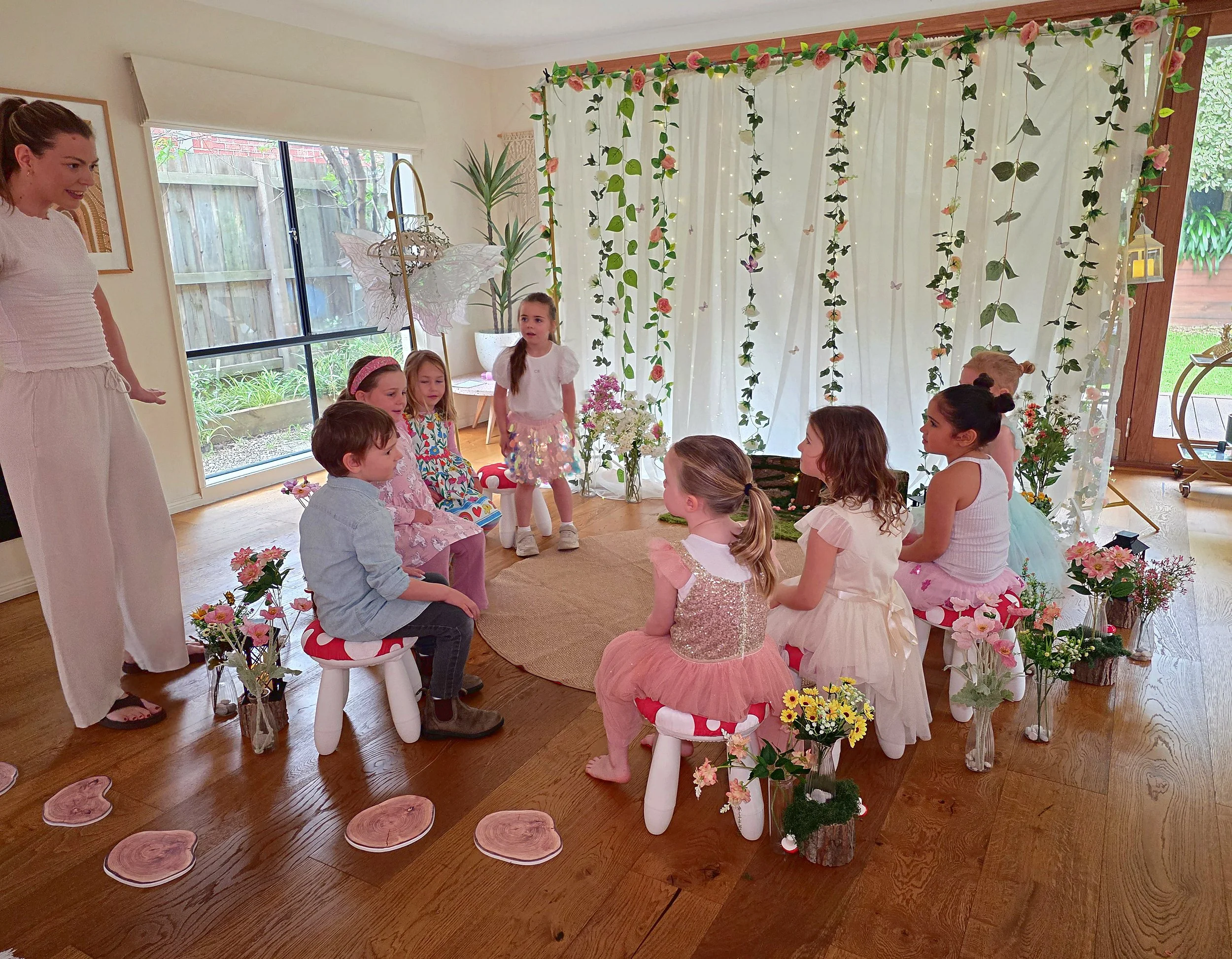 Children sitting on toadstool stools in the fairy circle with the party host