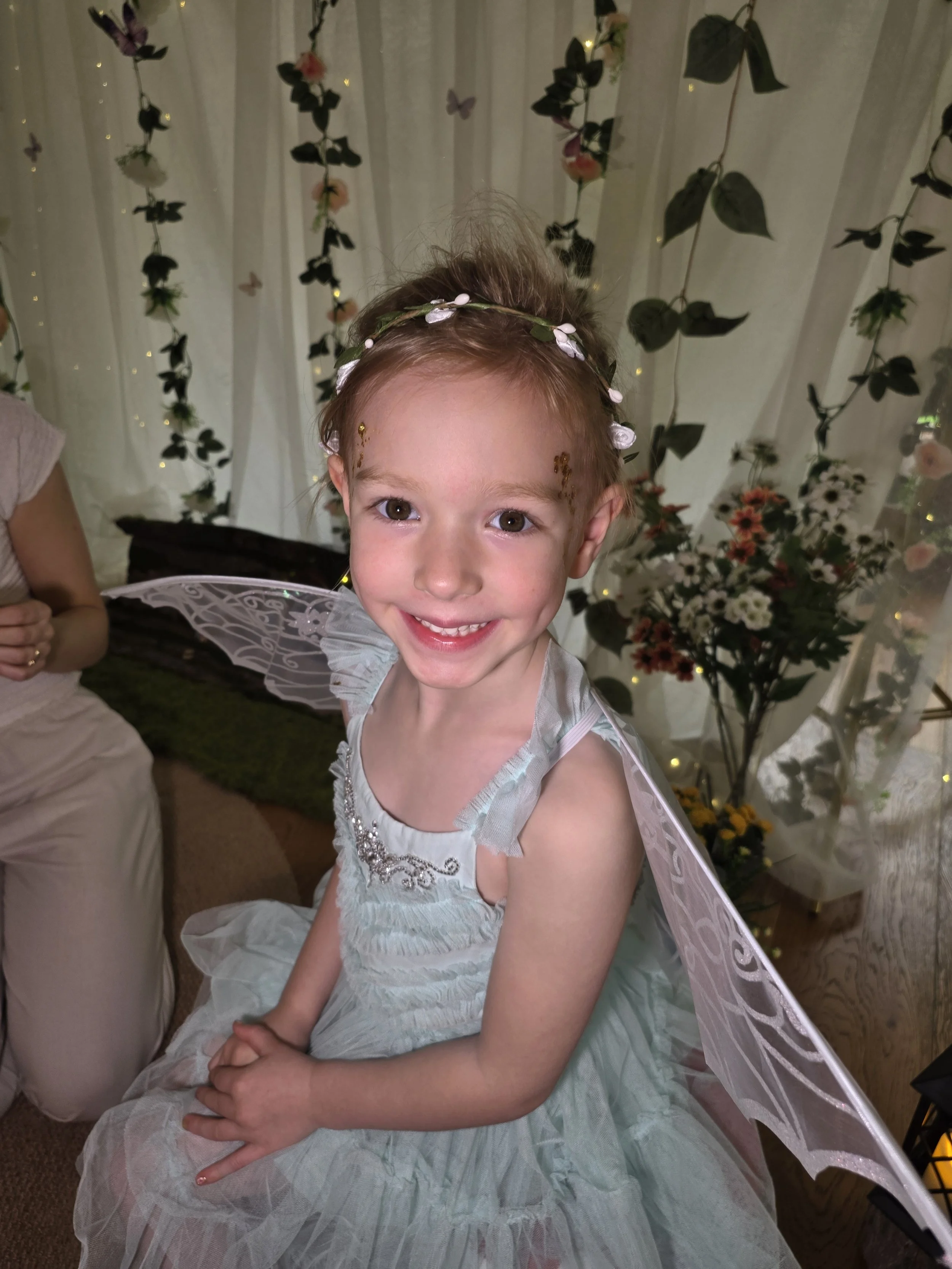 Smiling girl in fairy wings and a flower crown at an Enchanted Garden birthday party