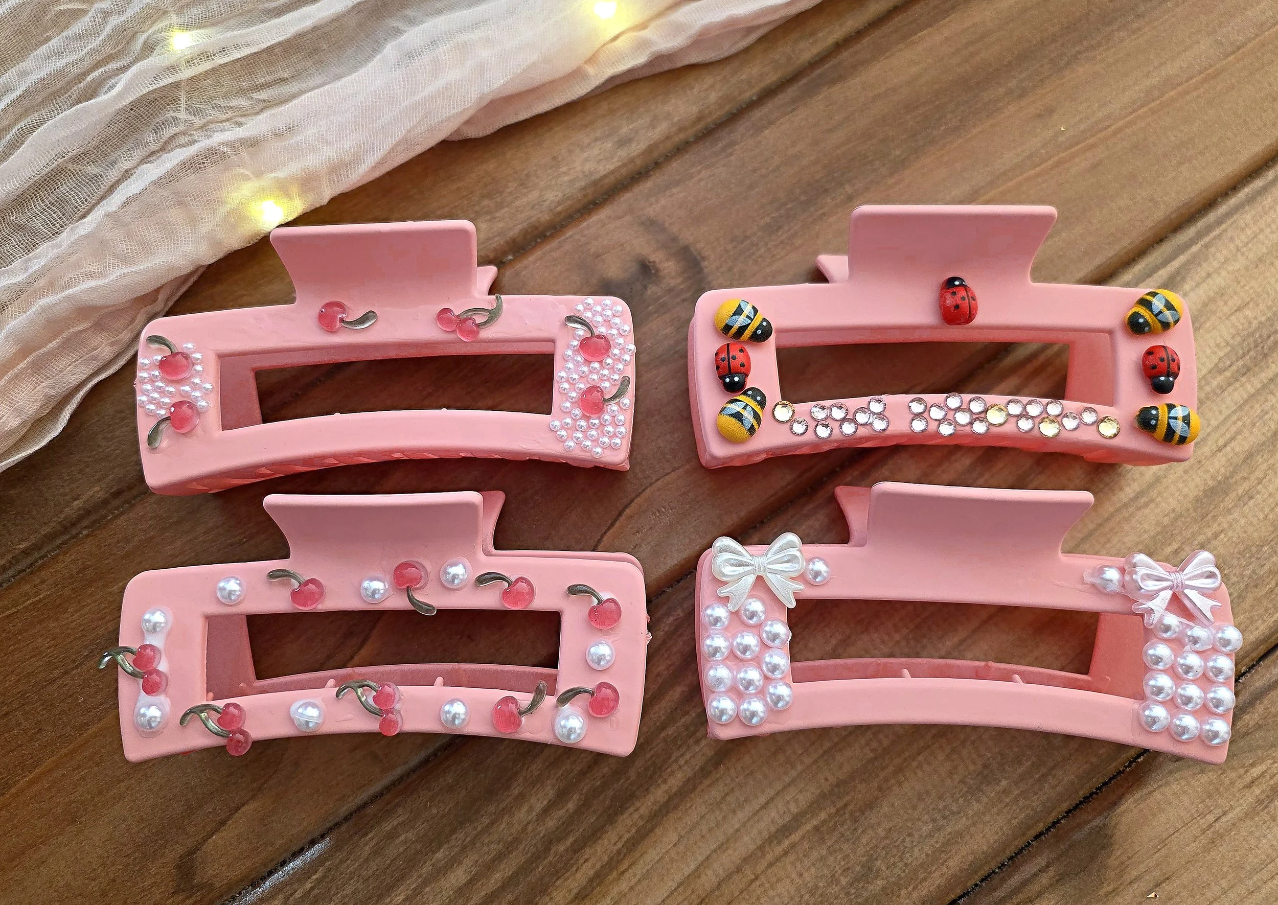 Four pink claw hair clips decorated with pearls, bows, cherries and ladybugs at a spa party