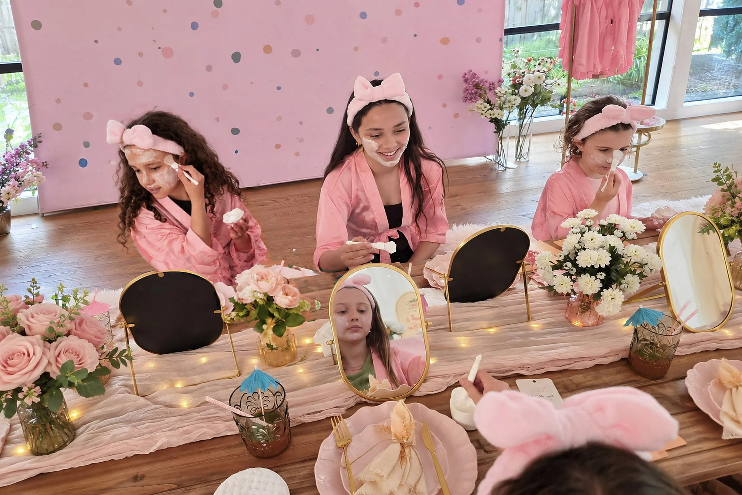 Girls in pink robes and bow headbands enjoying face masks at a girls' spa party in Melbourne