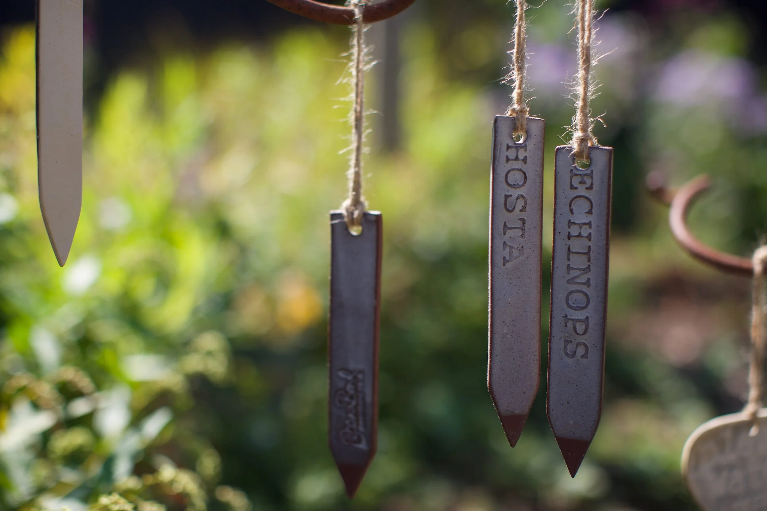 Ceramic ring-hung plant labels for Dahlia varieties displayed in a flower bed