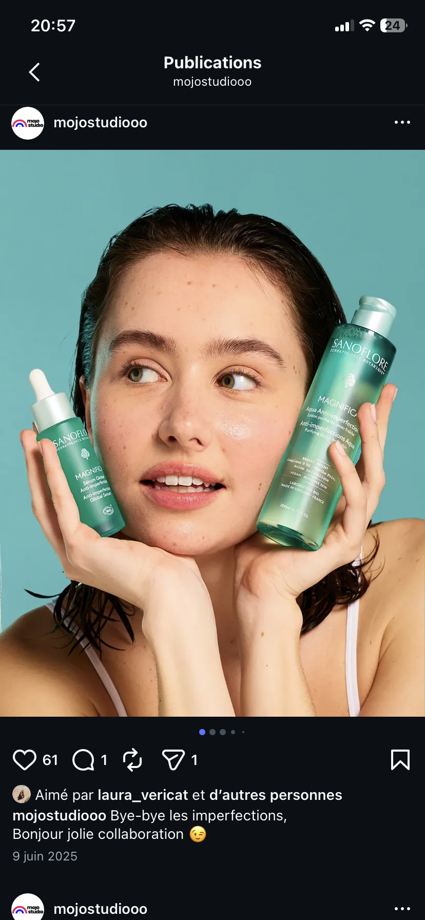 Une femme avec des cheveux courts et mouillés tient deux bouteilles de soin de la peau Sanoflore Magnifico contre ses joues, posant devant un fond bleu.