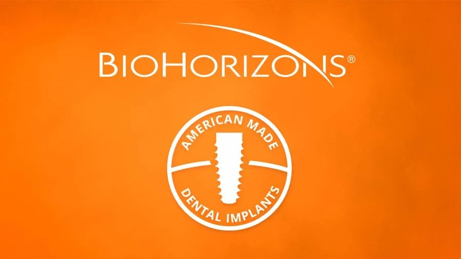 Orange background with the text 'Biohorizons' at the top, a circular logo with a dental implant in the center, and the words 'American Made Dental Implants' enclosed around the implant.