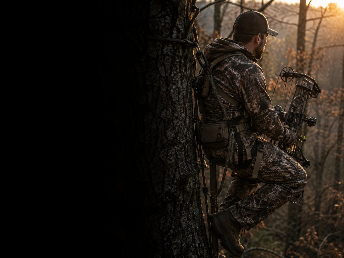 Man wearing camouflage clothing, cap, and hunting gear, sitting on a tree stand in a forest during sunset, holding a compound bow.