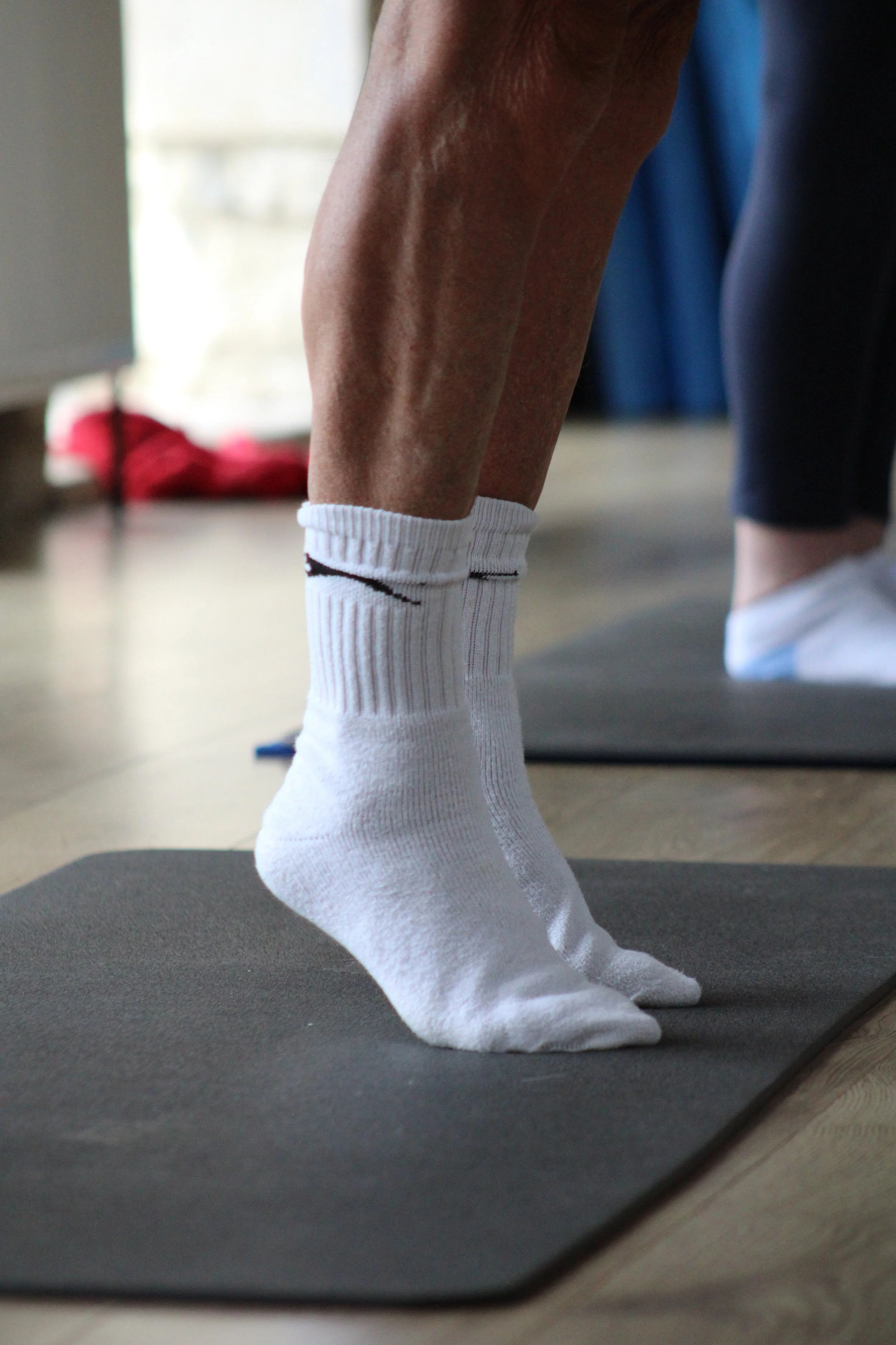 Close-up of a person wearing white socks and dark shorts, balancing on toes.