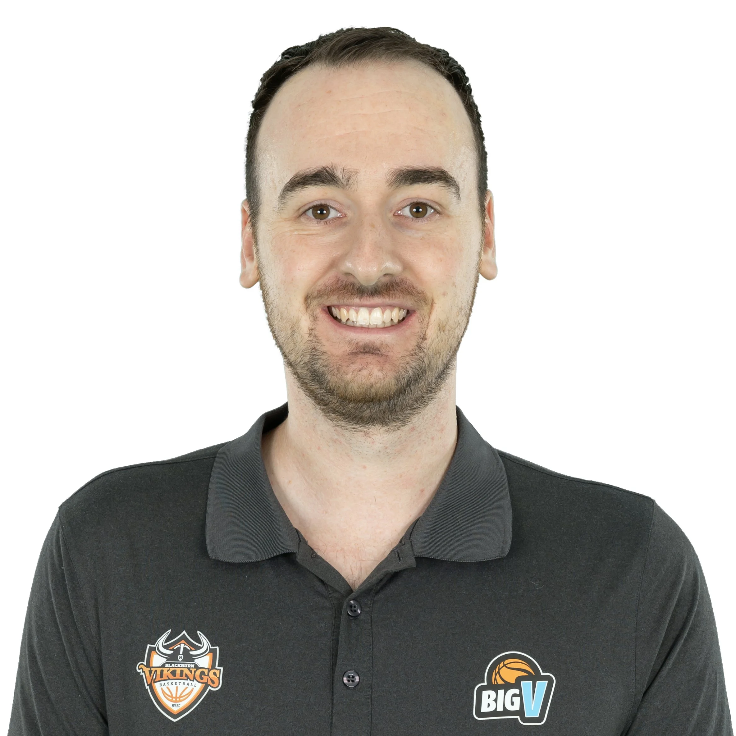 Close-up of a smiling man wearing a black jacket with two sports-themed patches: one for Blackburn Vikings basketball and another for BigV basketball, against a white background.