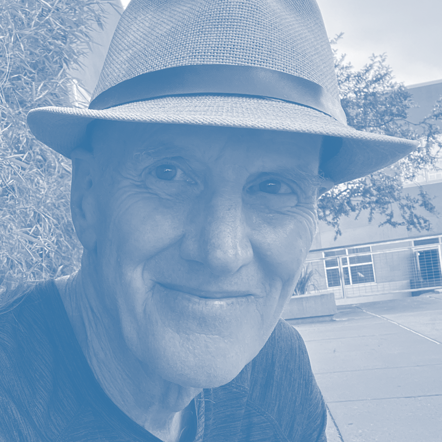 Close-up of Dan Murray wearing a straw hat outdoors with trees in the background.
