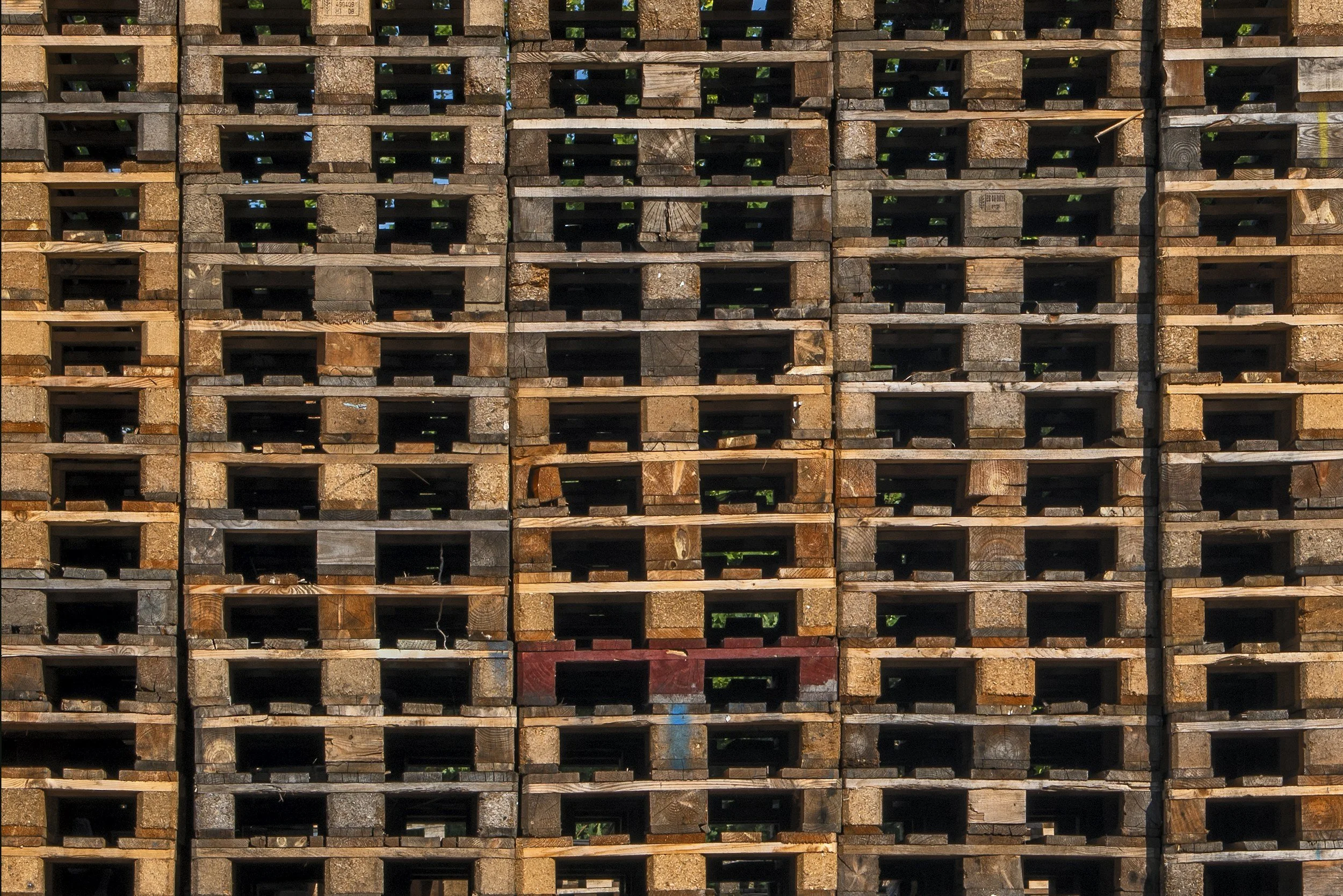 Stacked wooden pallets with some minor paint markings, arranged in a grid pattern.