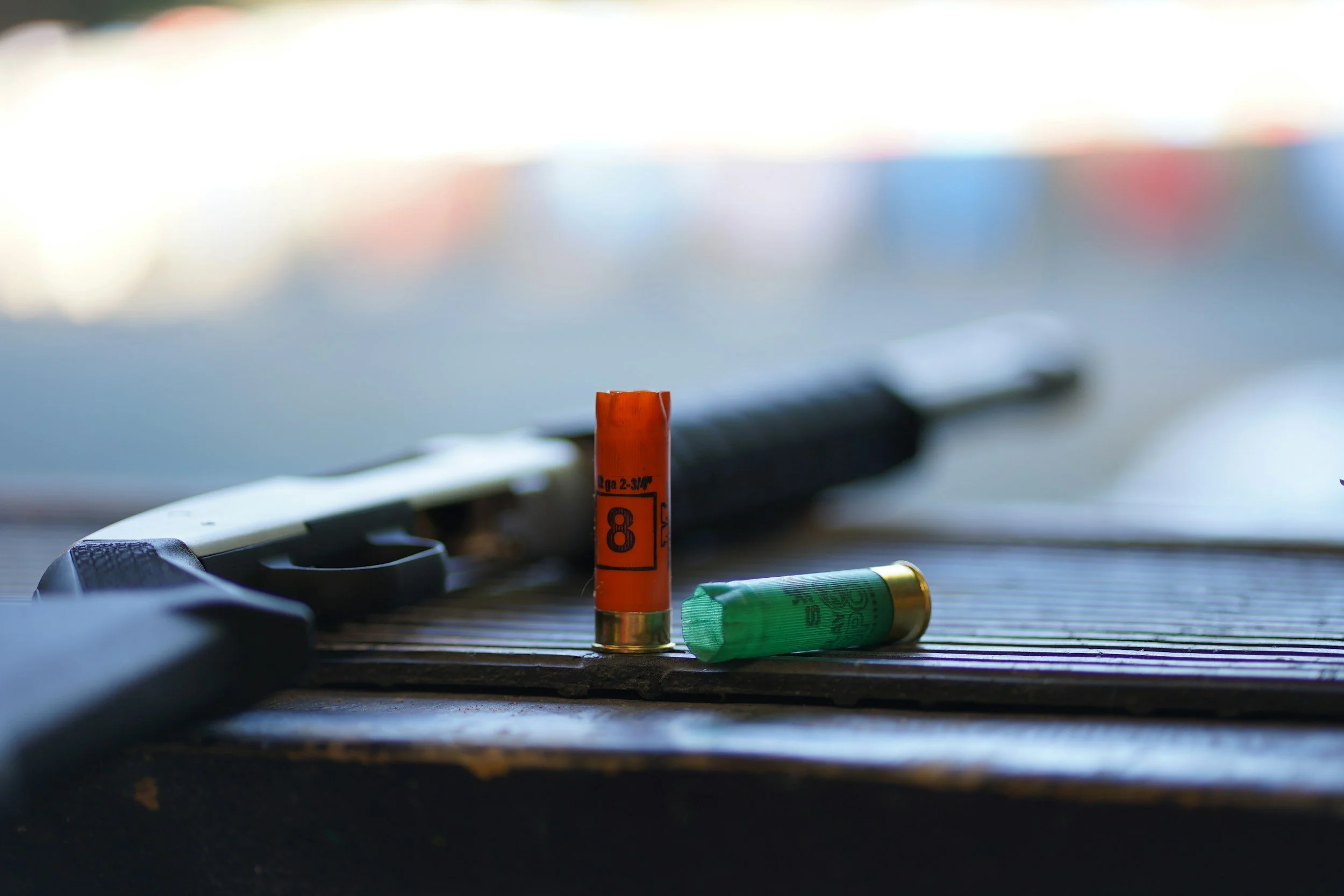 Shotgun shells and a hunting knife on a wooden surface with a blurred background.