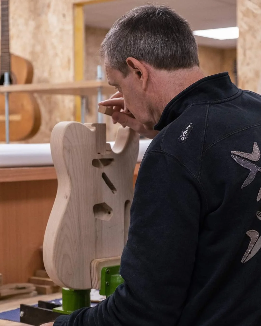 Un homme travaille sur une sculpture en bois dans un atelier, utilisant une pièce en bois fixée sur une machine.