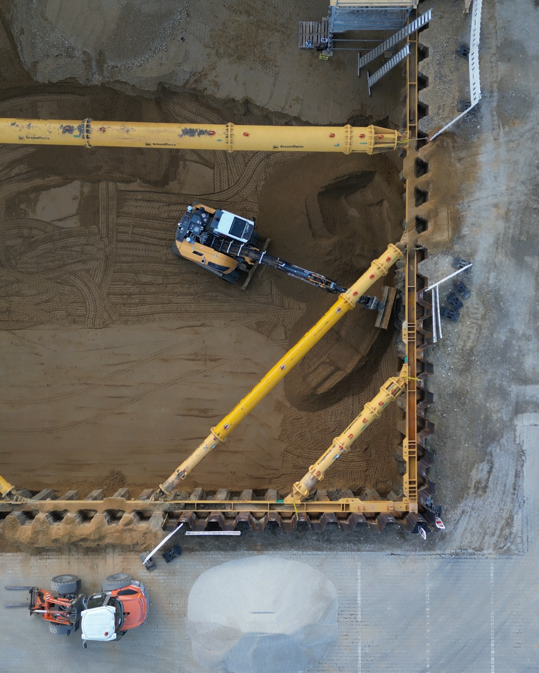 Blick von oben auf eine Baustelle mit einer Baumaschine, die den Bodenaustausch für ein Tiefbauprojekt vornimmt