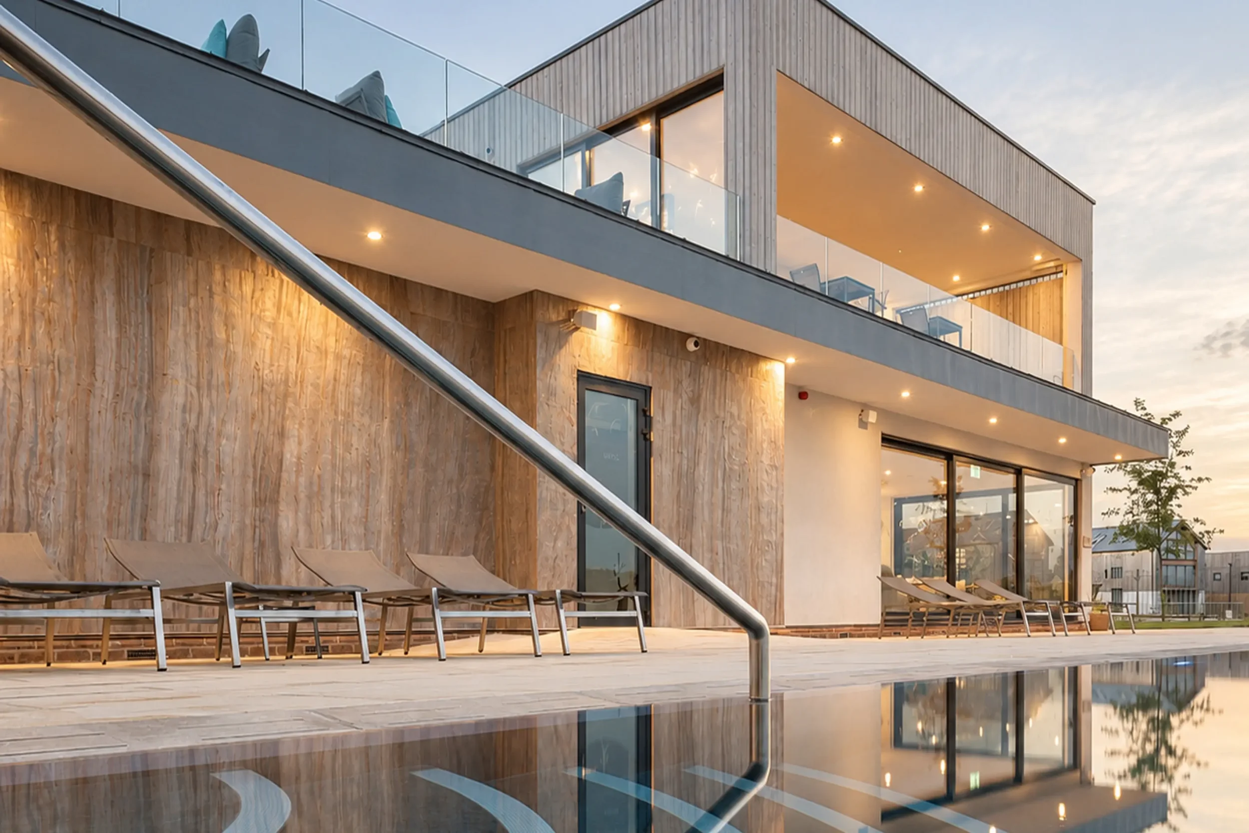 Outdoor pool at Silverlake Hurricane Spa in Dorset, with the contemporary spa building illuminated at dusk.