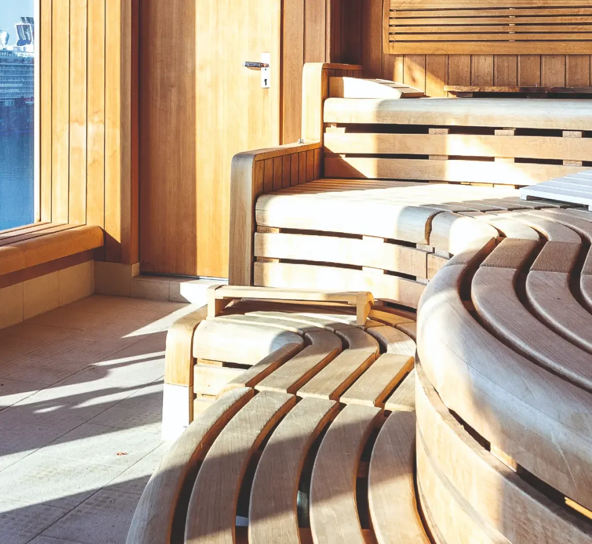 Bespoke timber sauna interior with sculpted curved seating arranged across multiple levels.