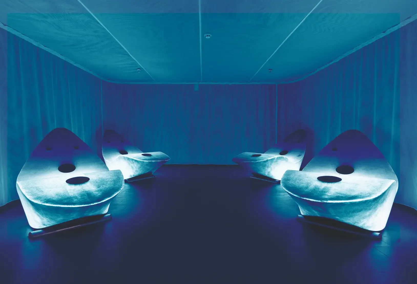 Dry flotation treatment room with individual flotation beds and atmospheric blue lighting.