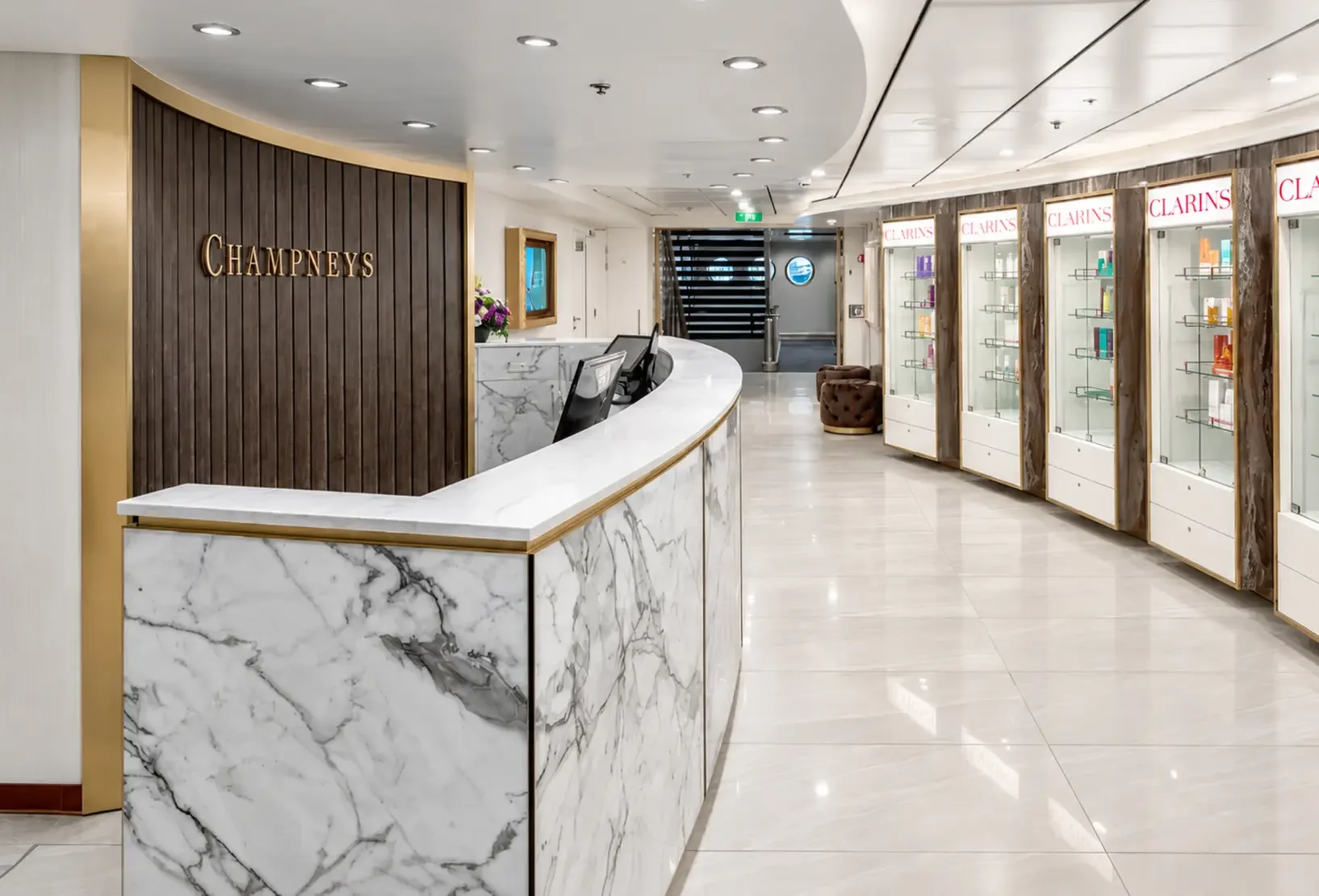 Spa reception and retail area with bespoke desk, display shelving and warm metallic detailing.