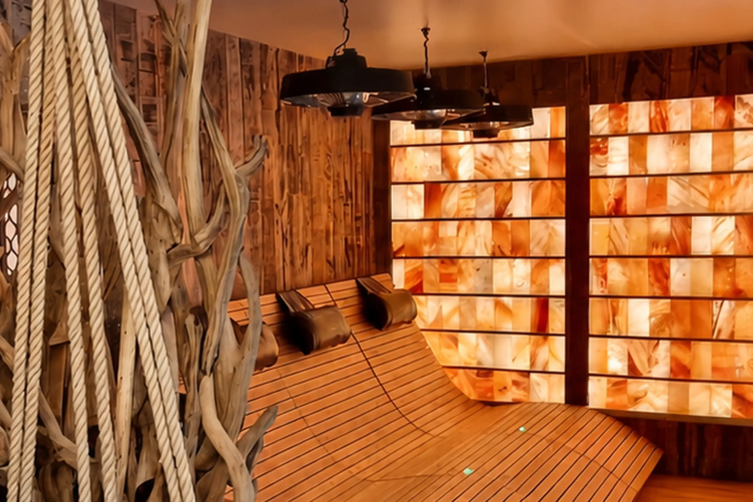 Infrared relaxation room featuring illuminated Himalayan salt walls, timber loungers and integrated light therapy for a restorative spa experience.