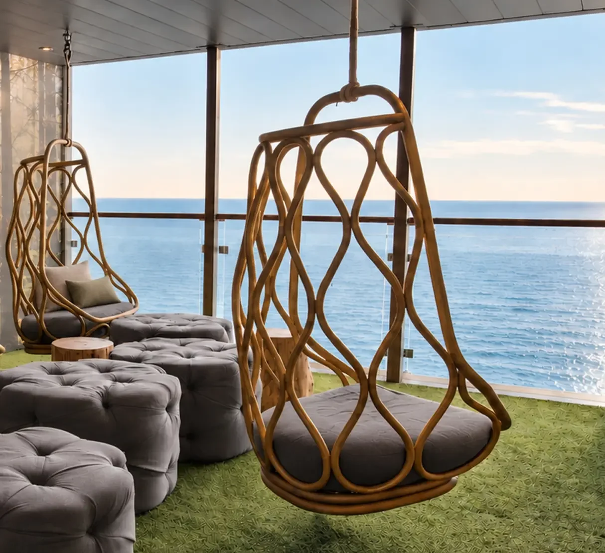Hanging relaxation pods positioned beside full-height glazing with views out to sea.