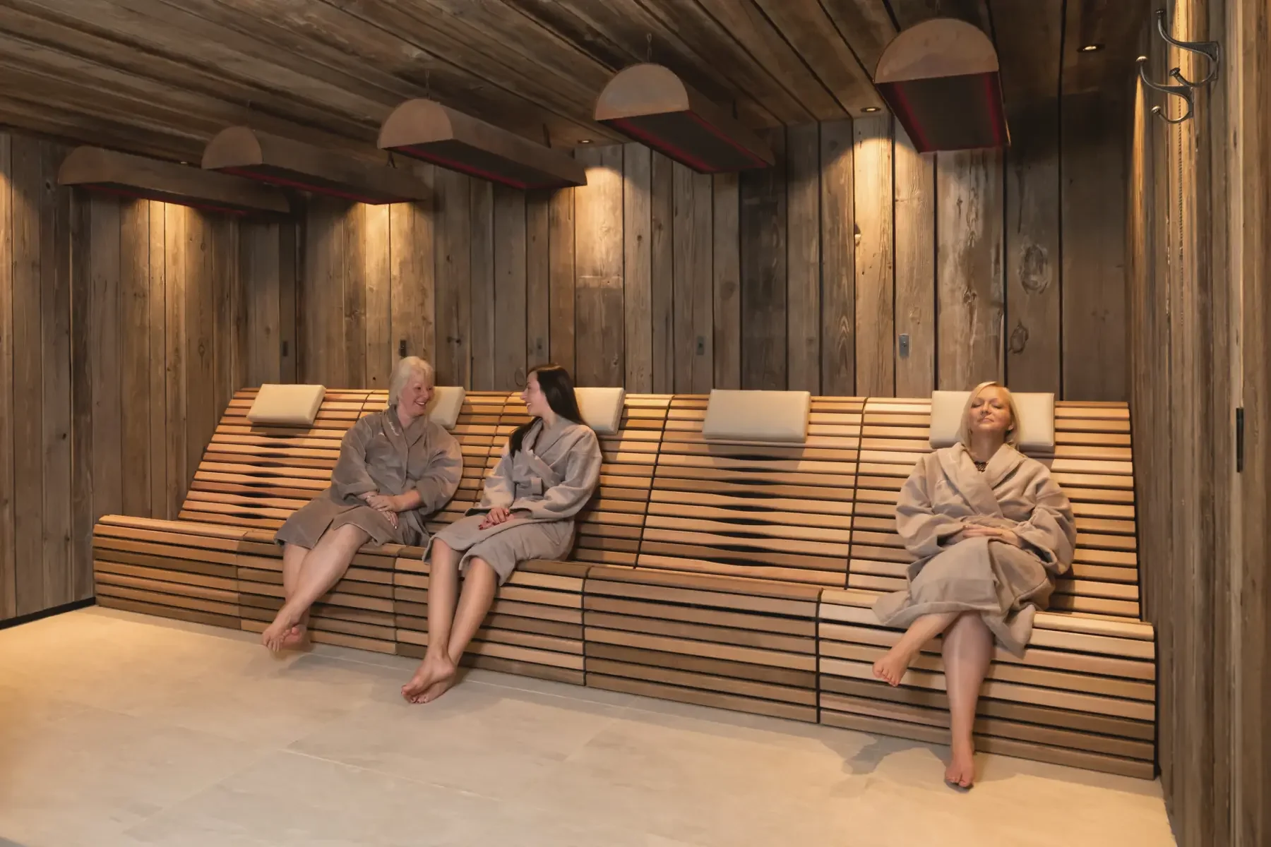 Three women relaxing on the infrared therapy bench at Homefield Grange designed by Butterscotch Design