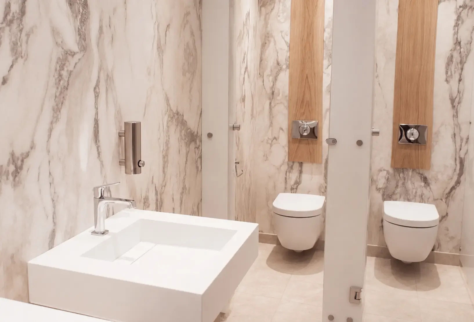 Spa washrooms with contemporary white basins, natural stone walls and timber detailing.